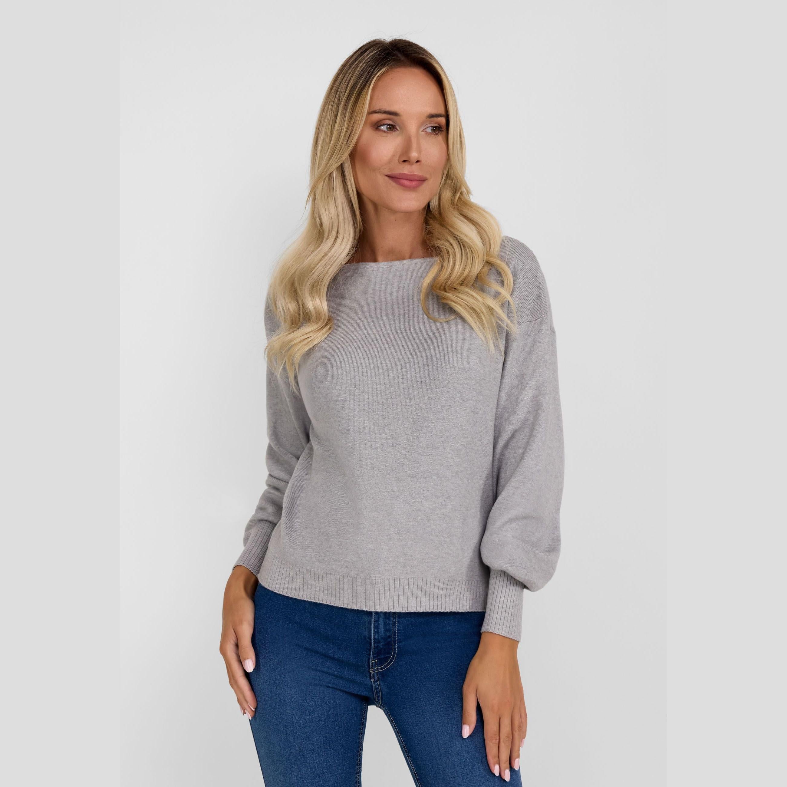 Blonde woman wearing grey boat neck jumper with blue jeans against white background, front view showing relaxed fit and wide neckline