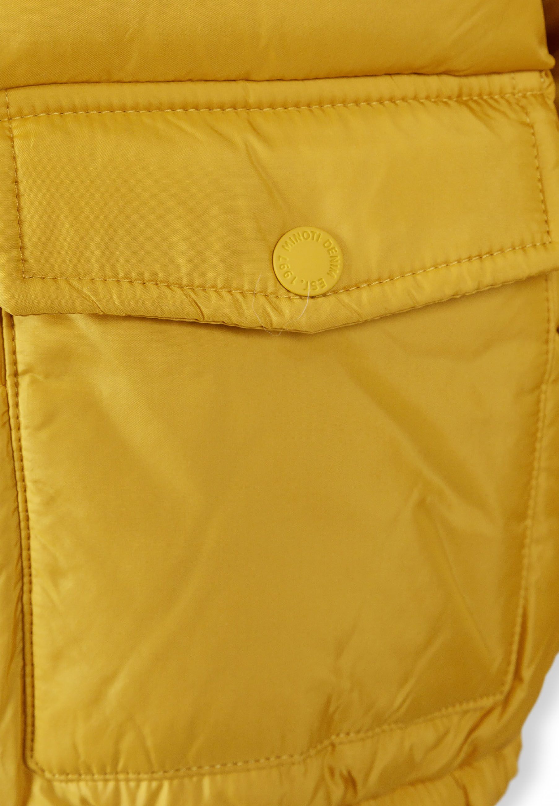 Detail of mustard teddy lined jacket showing flap pocket and branded badge.