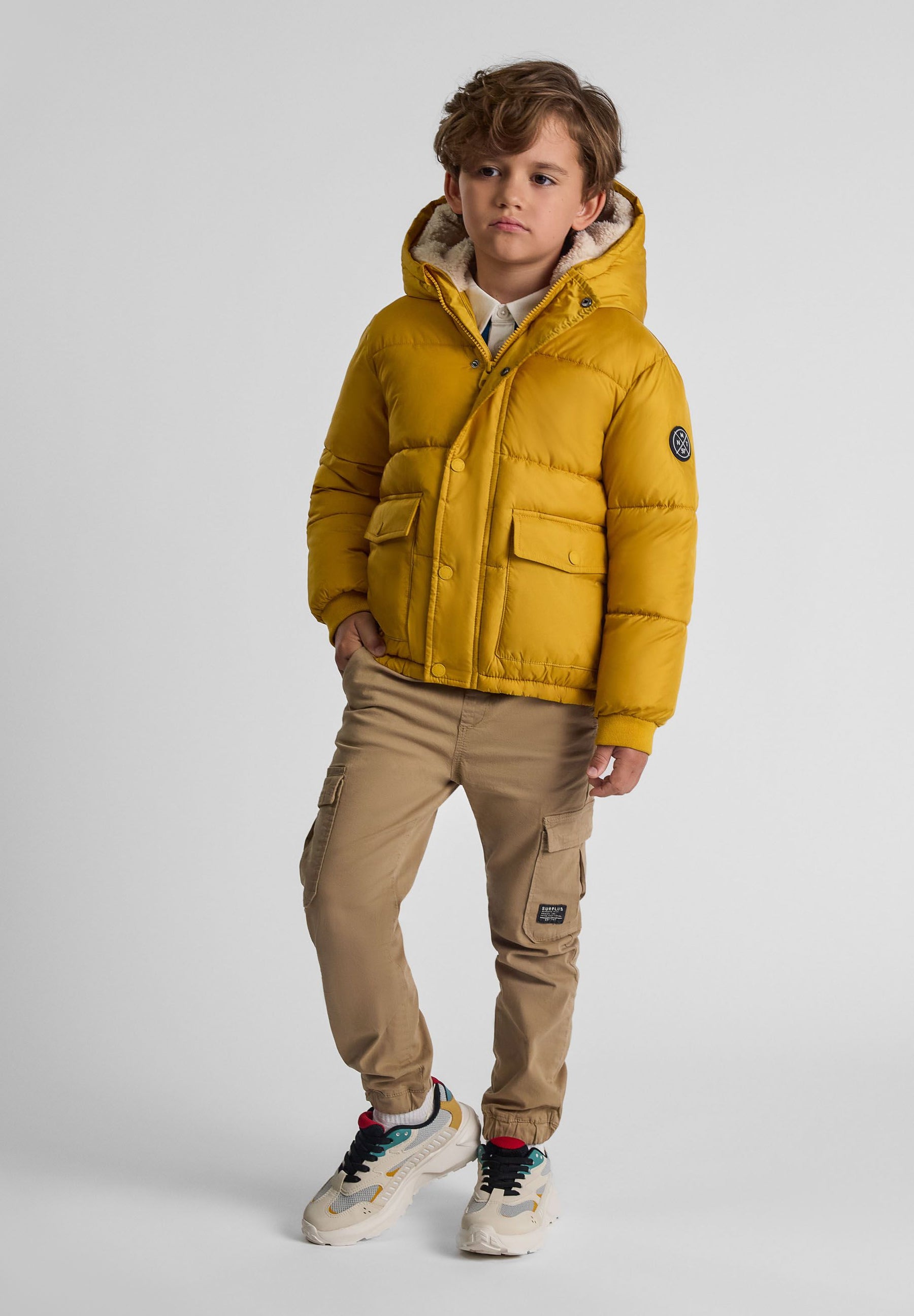 Boys mustard teddy lined jacket with hood, front view, featuring two flap pockets and a branded badge.