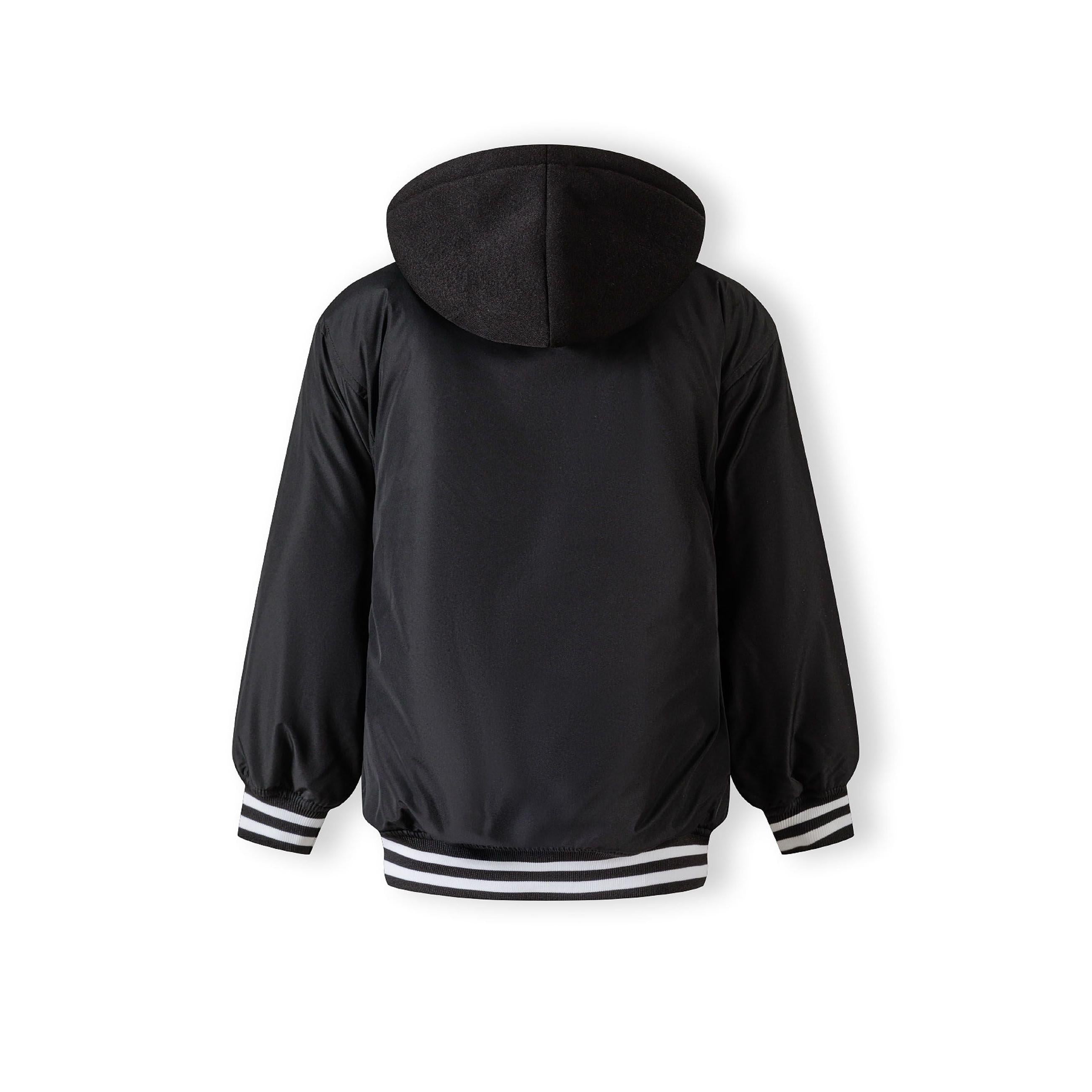 Flat lay of black baseball jacket with detachable hood showing snap button front closure and contrasting white striped ribbed cuffs and waistband