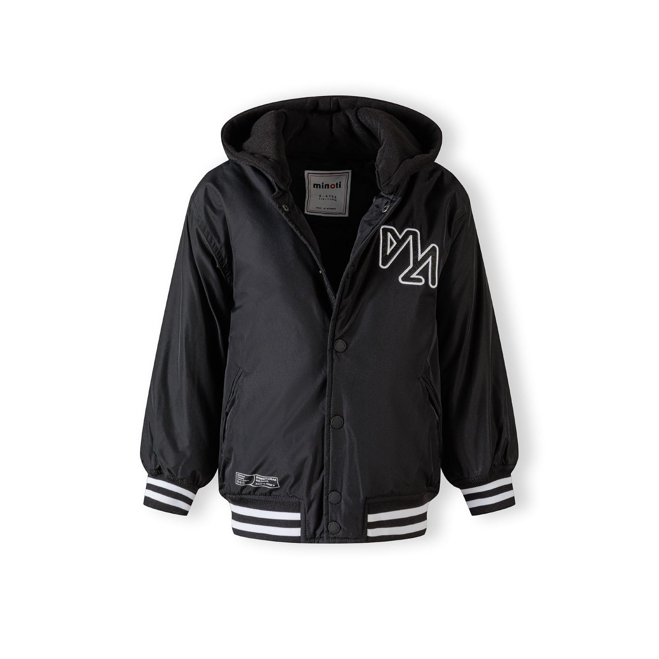 Flat lay of black baseball jacket with detachable hood showing snap button front closure and contrasting white striped ribbed cuffs and waistband