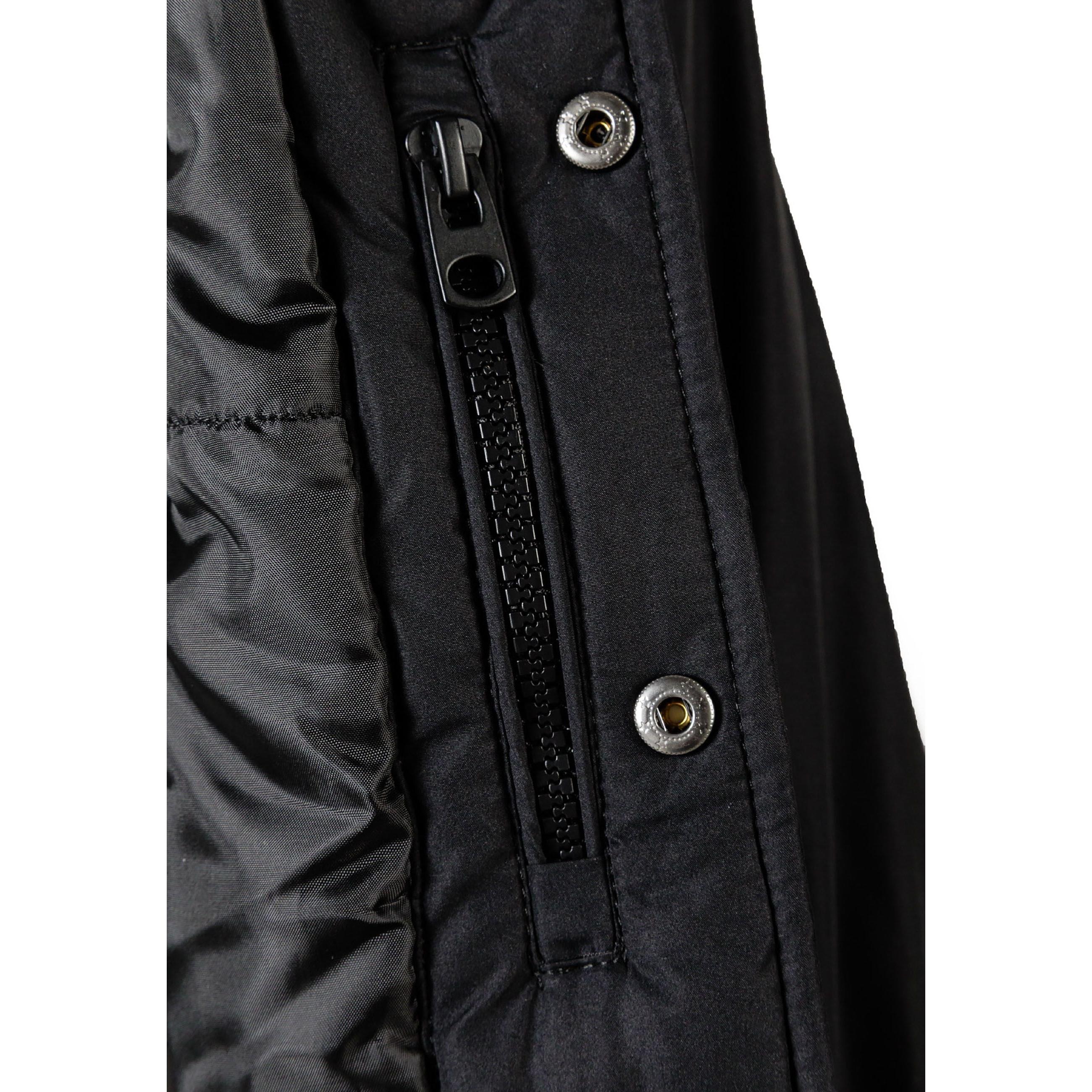 Flat lay of black baseball jacket with detachable hood showing snap button front closure and contrasting white striped ribbed cuffs and waistband