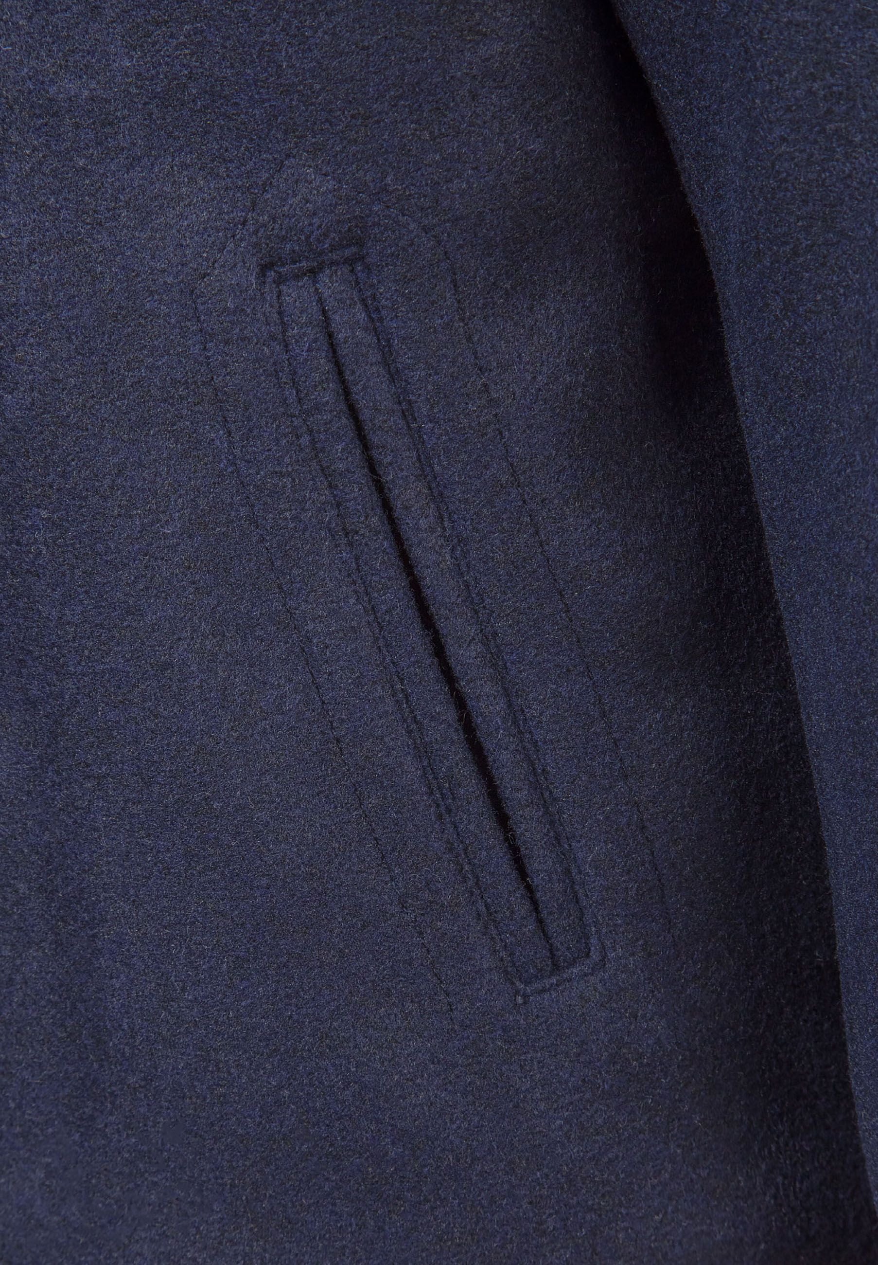 Detail of a navy boys coat showing a jetted pocket.