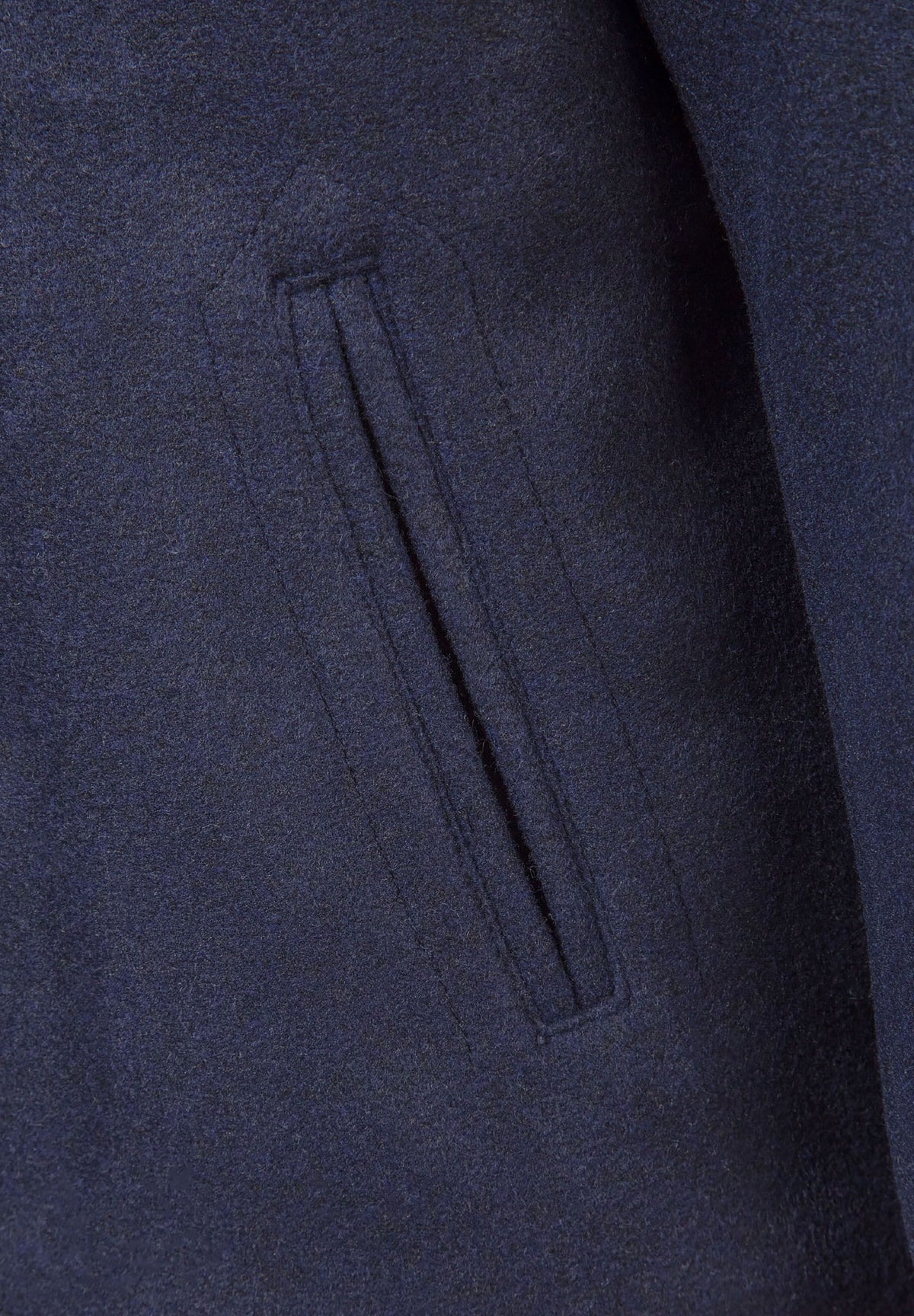 Close-up of a narrow vertical welt pocket in the navy pea coat's textured fabric.