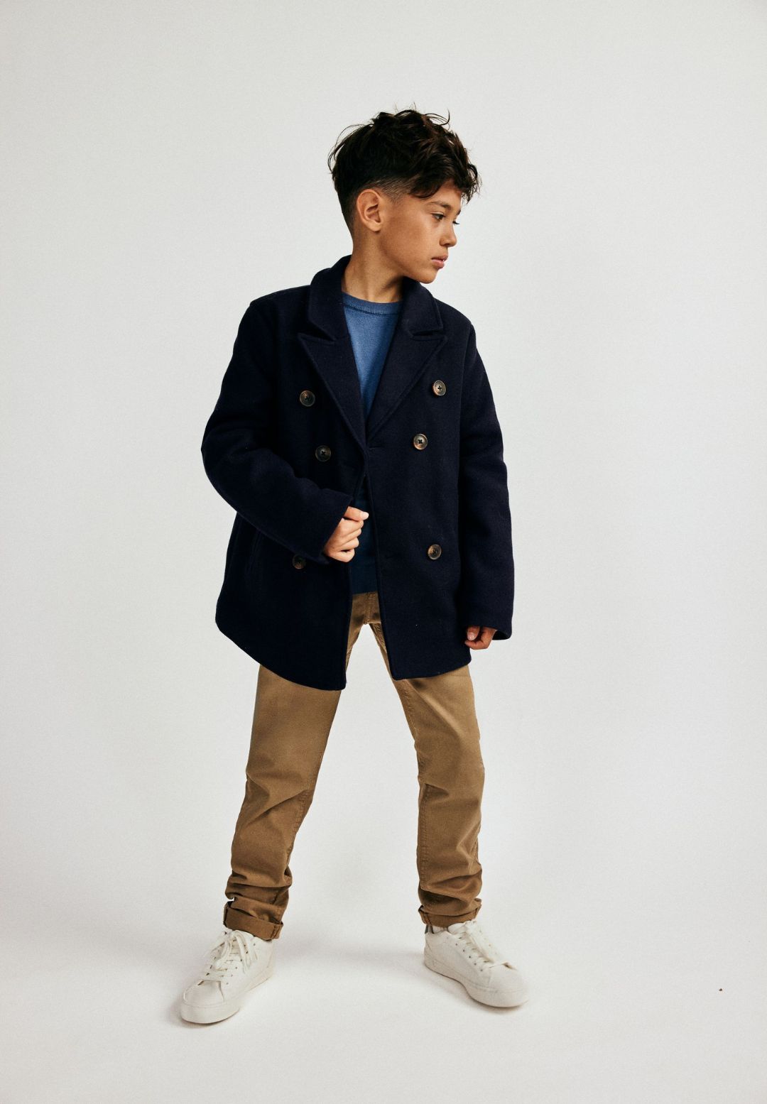 Boys navy double breasted coat with lapel, front view, featuring tonal buttons and jetted pockets.