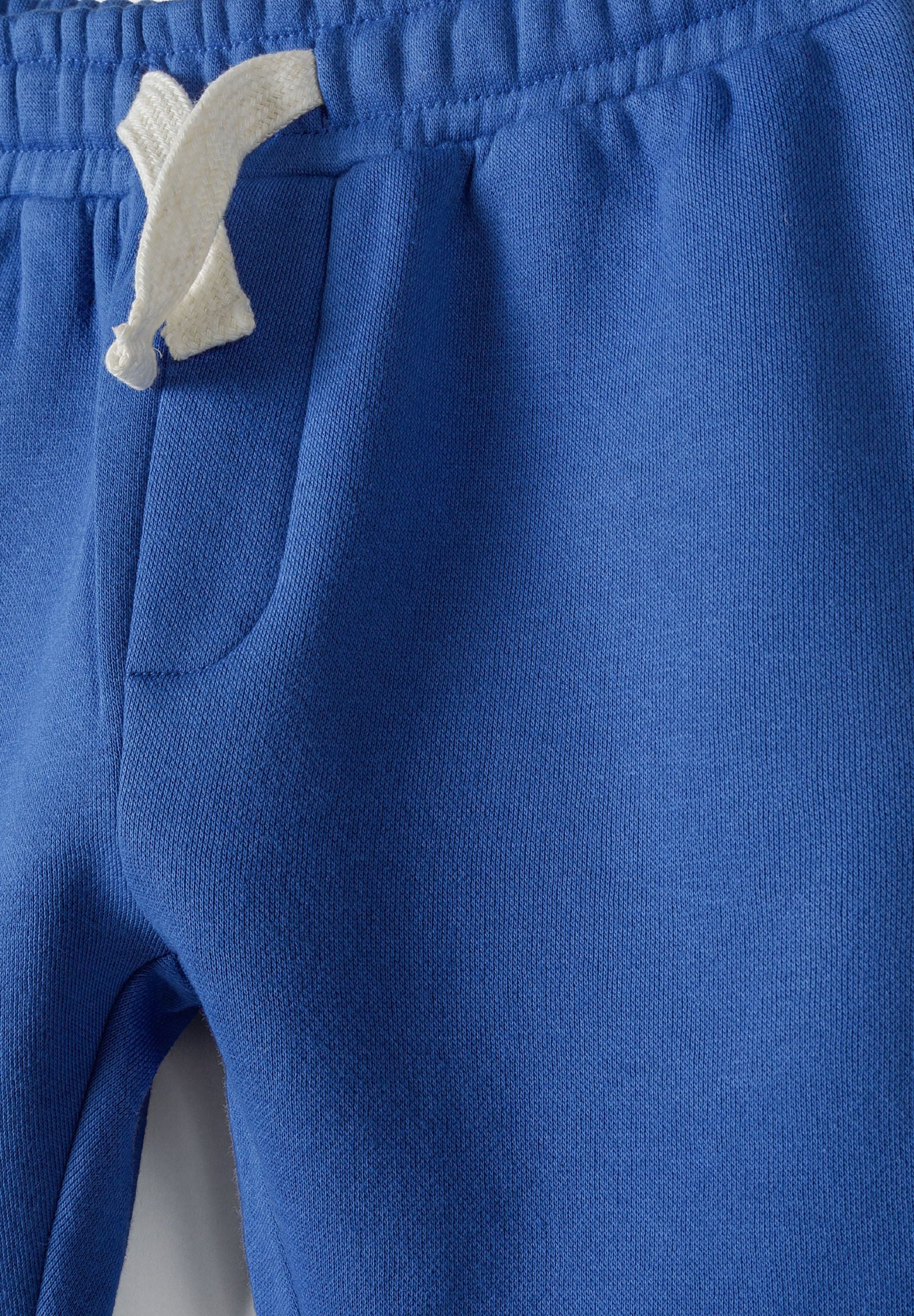 Close-up of cobalt blue joggers featuring an adjustable waistband and side pocket.