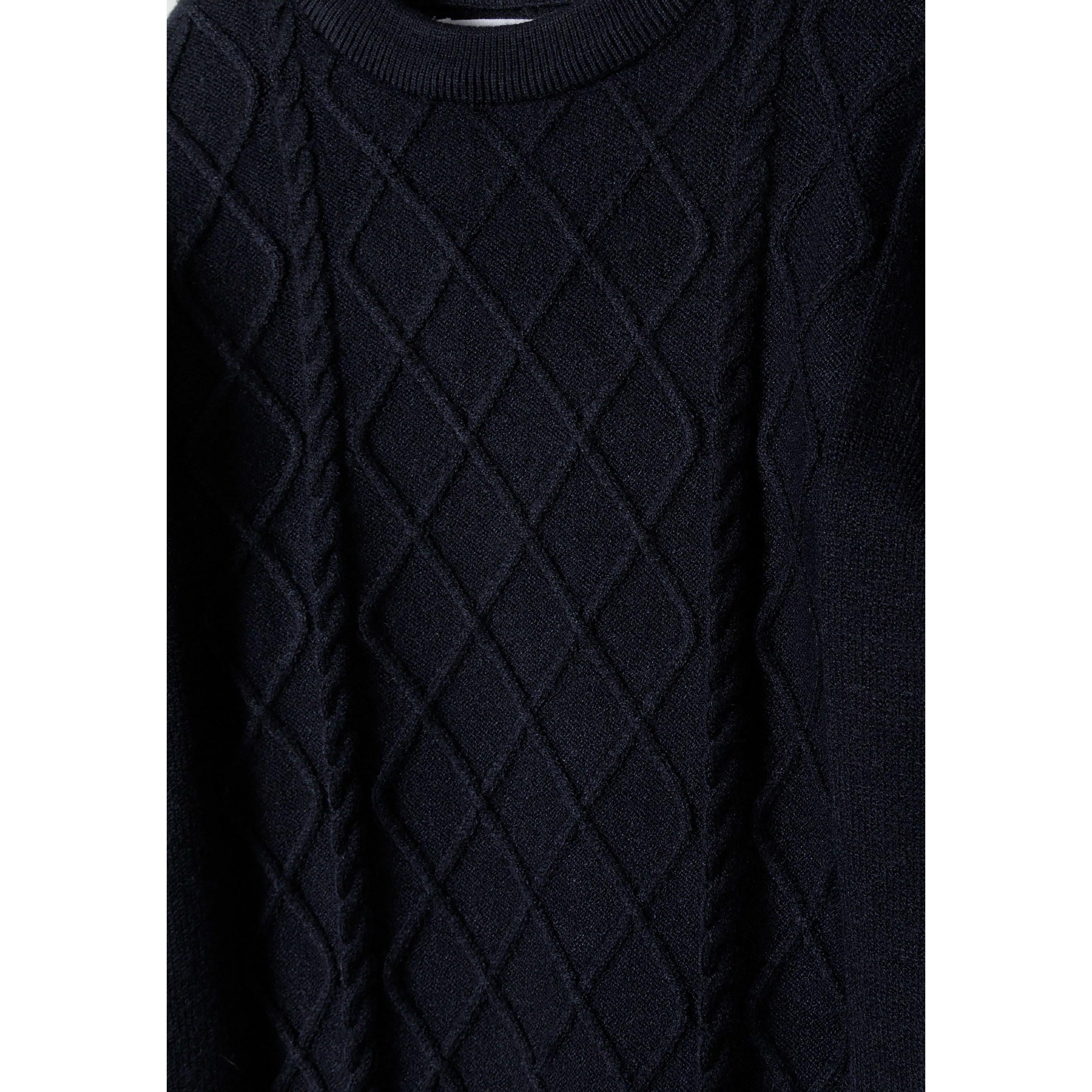 Close-up detail of navy cable knit jumper showing intricate raised diamond texture pattern and crew neck collar construction