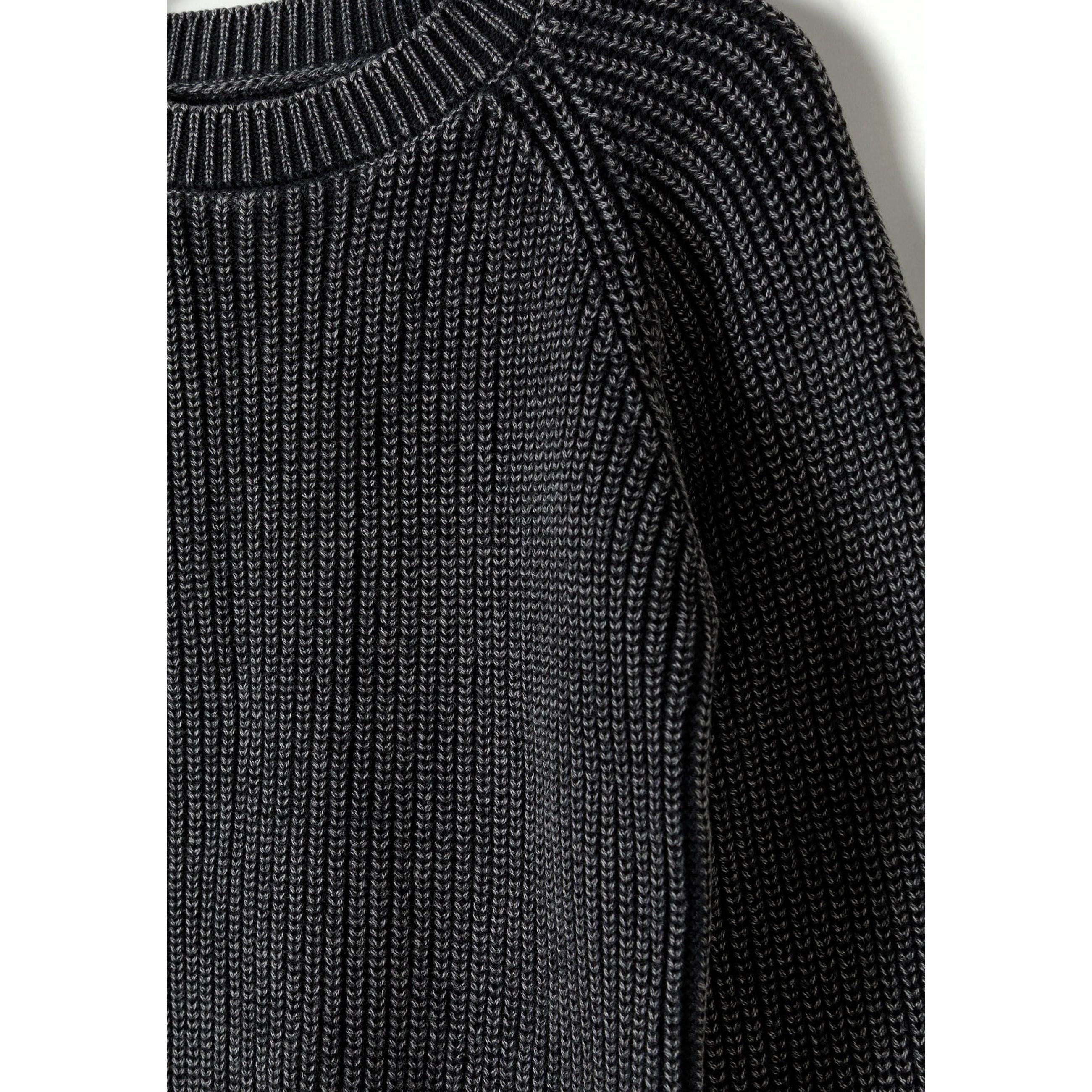 Close-up detail of black acid wash jumper showing ribbed knit pattern and raglan sleeve seam construction