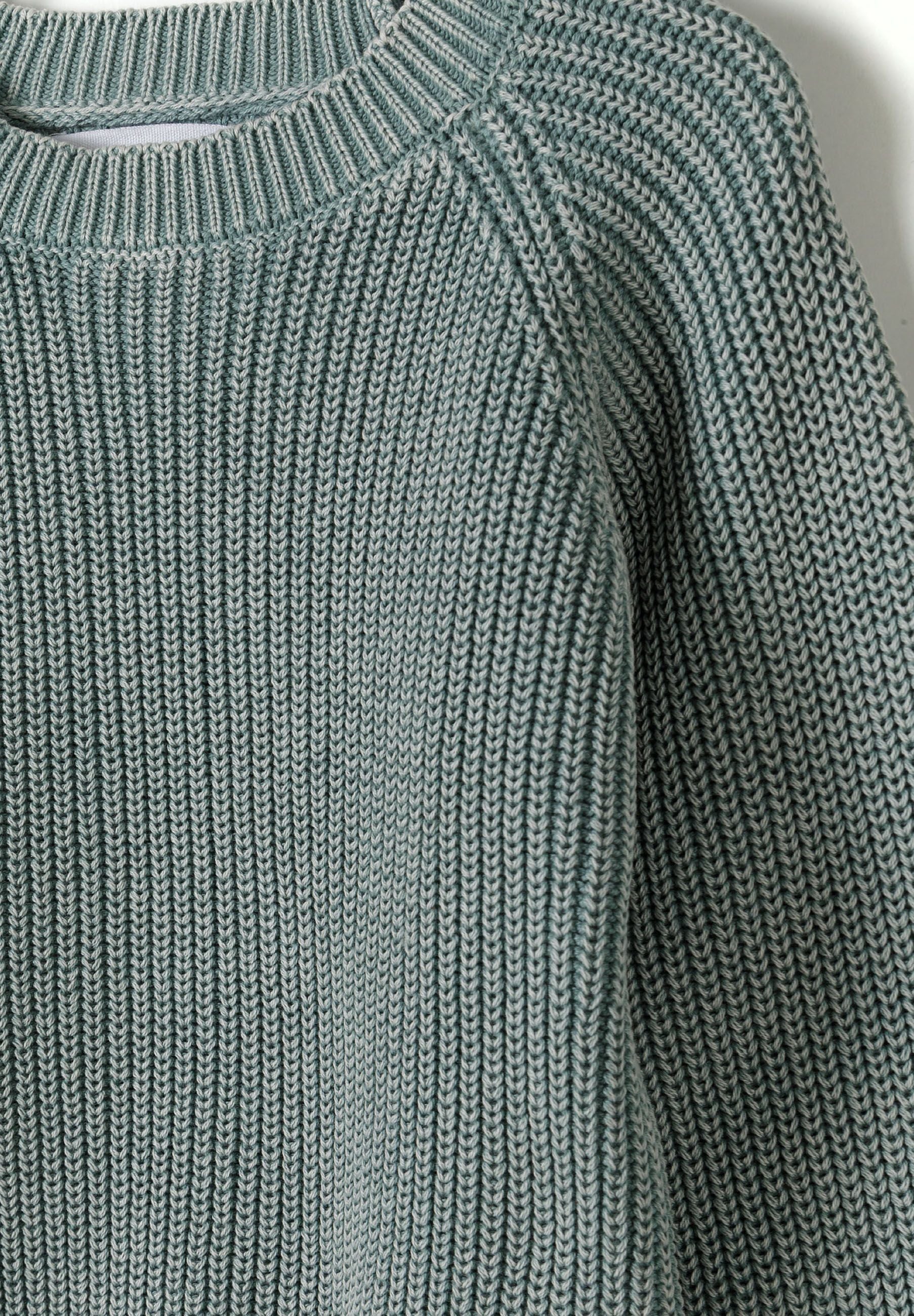 Close-up of a boys cotton jumper in a washed effect with ribbed texture and crew neckline.