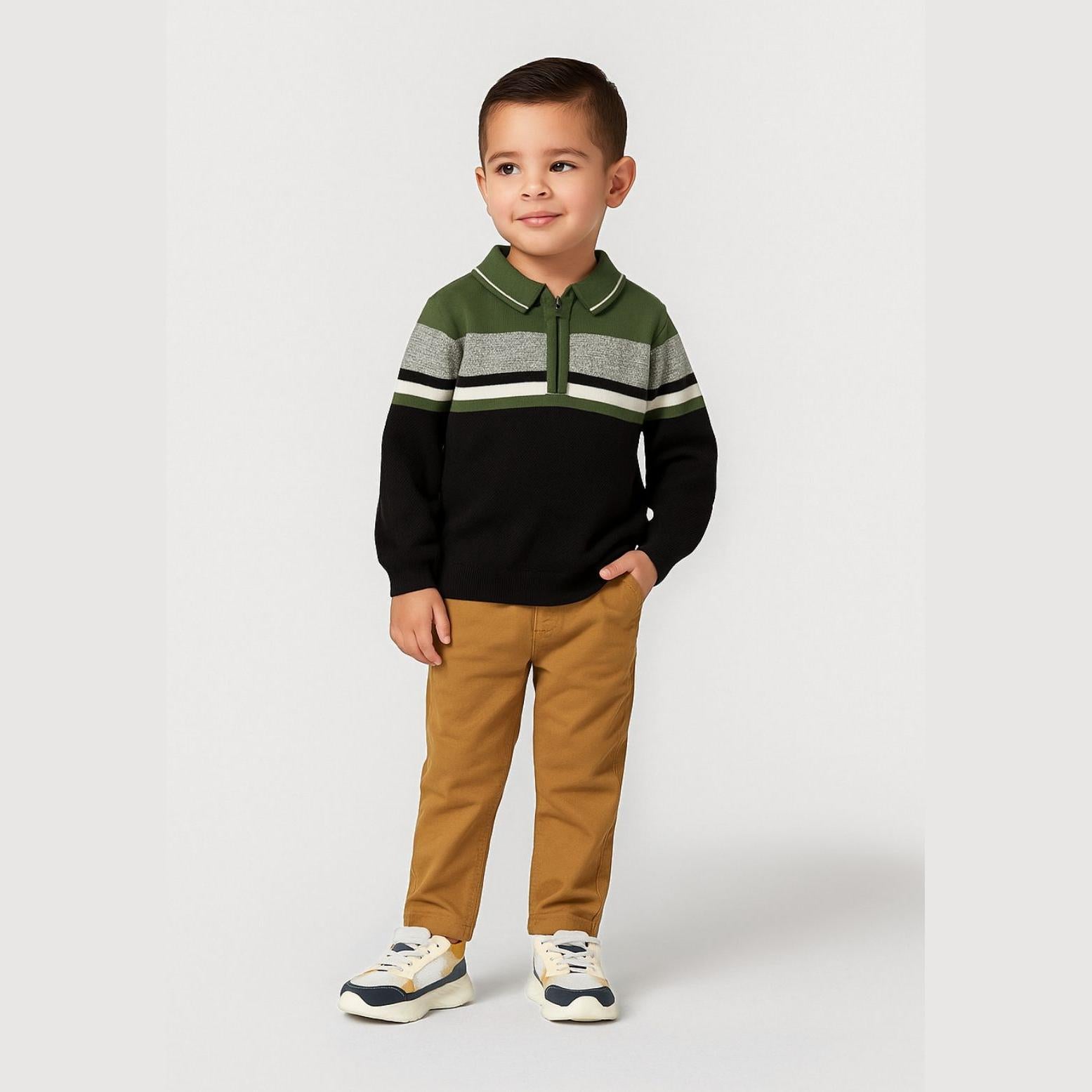 Young boy wearing khaki striped polo jumper with quarter zip and mustard chinos, standing against light grey background