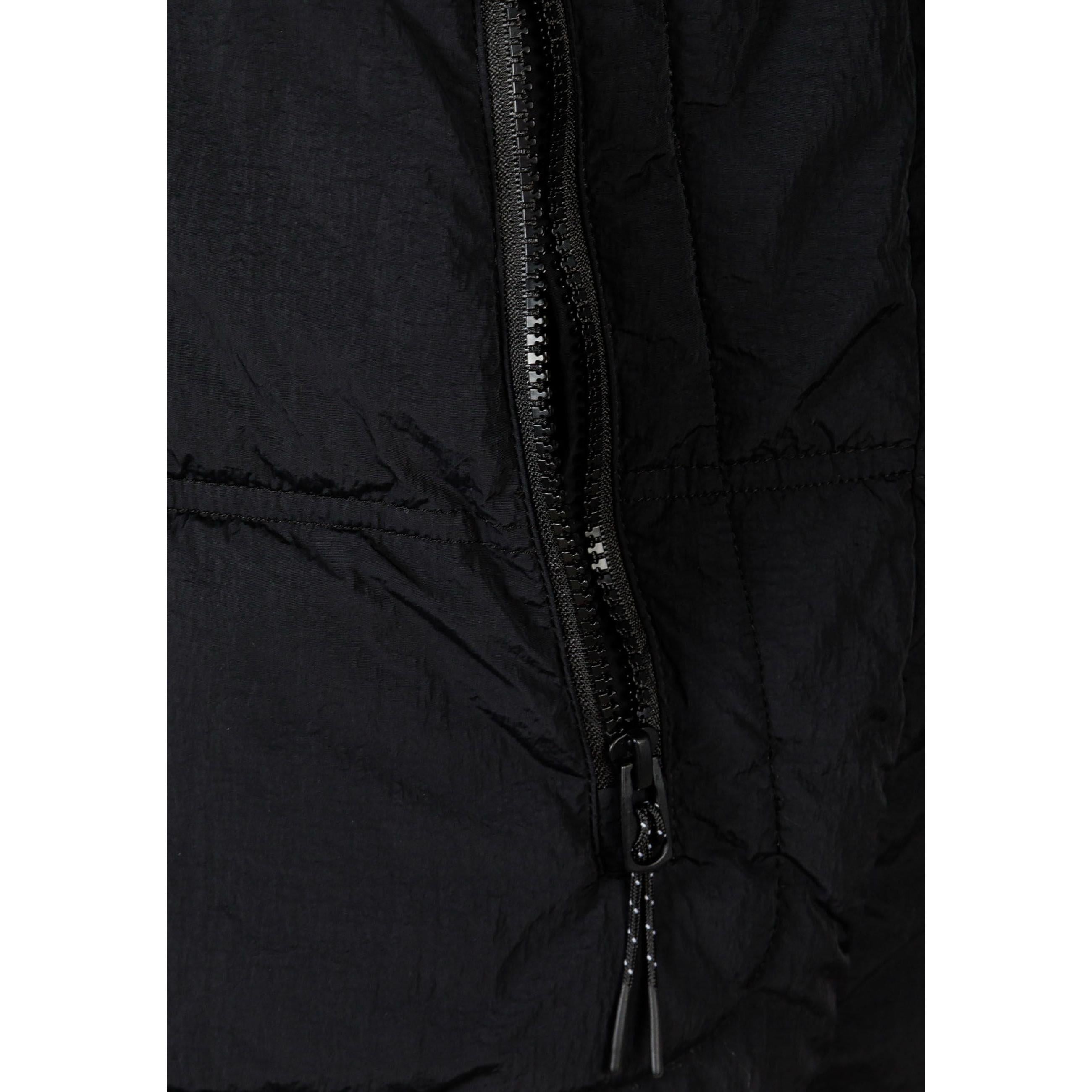 Close-up detail of black quilted fabric showing rectangular RESPECT PERFORMANCE brand label with R logo on jacket sleeve