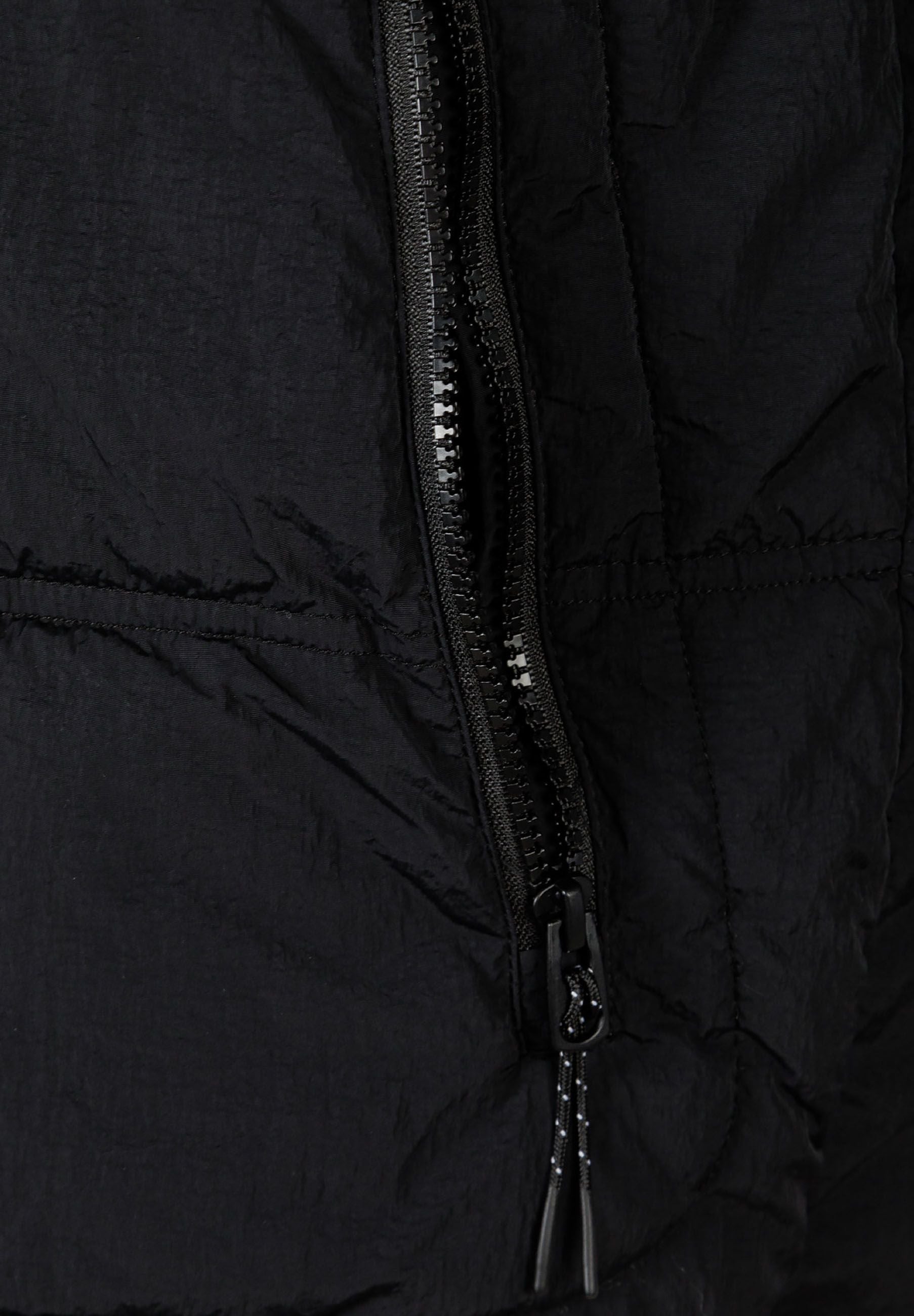 Detail of a black quilted boys jacket featuring a zip pocket.