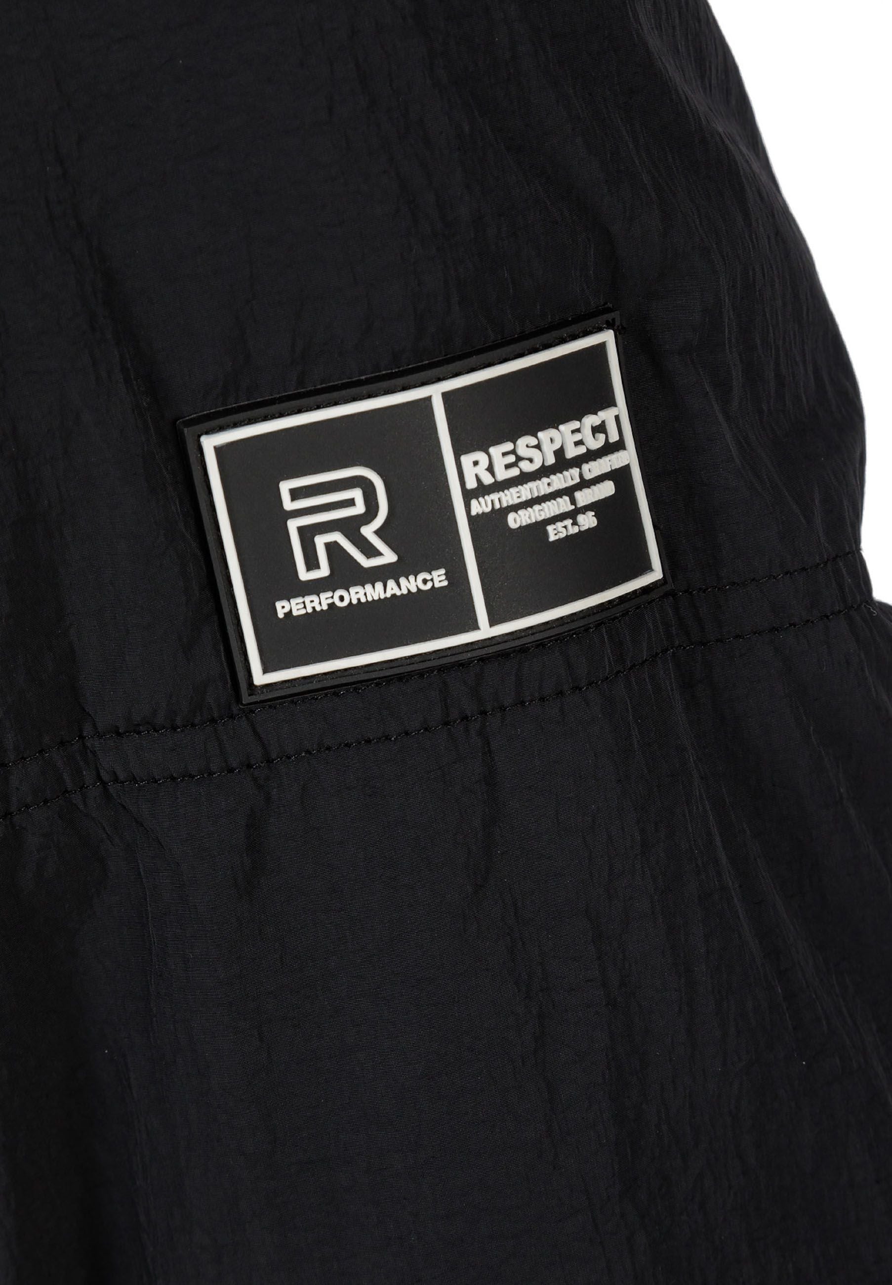 Detail of a black quilted jacket featuring a rubber logo patch.