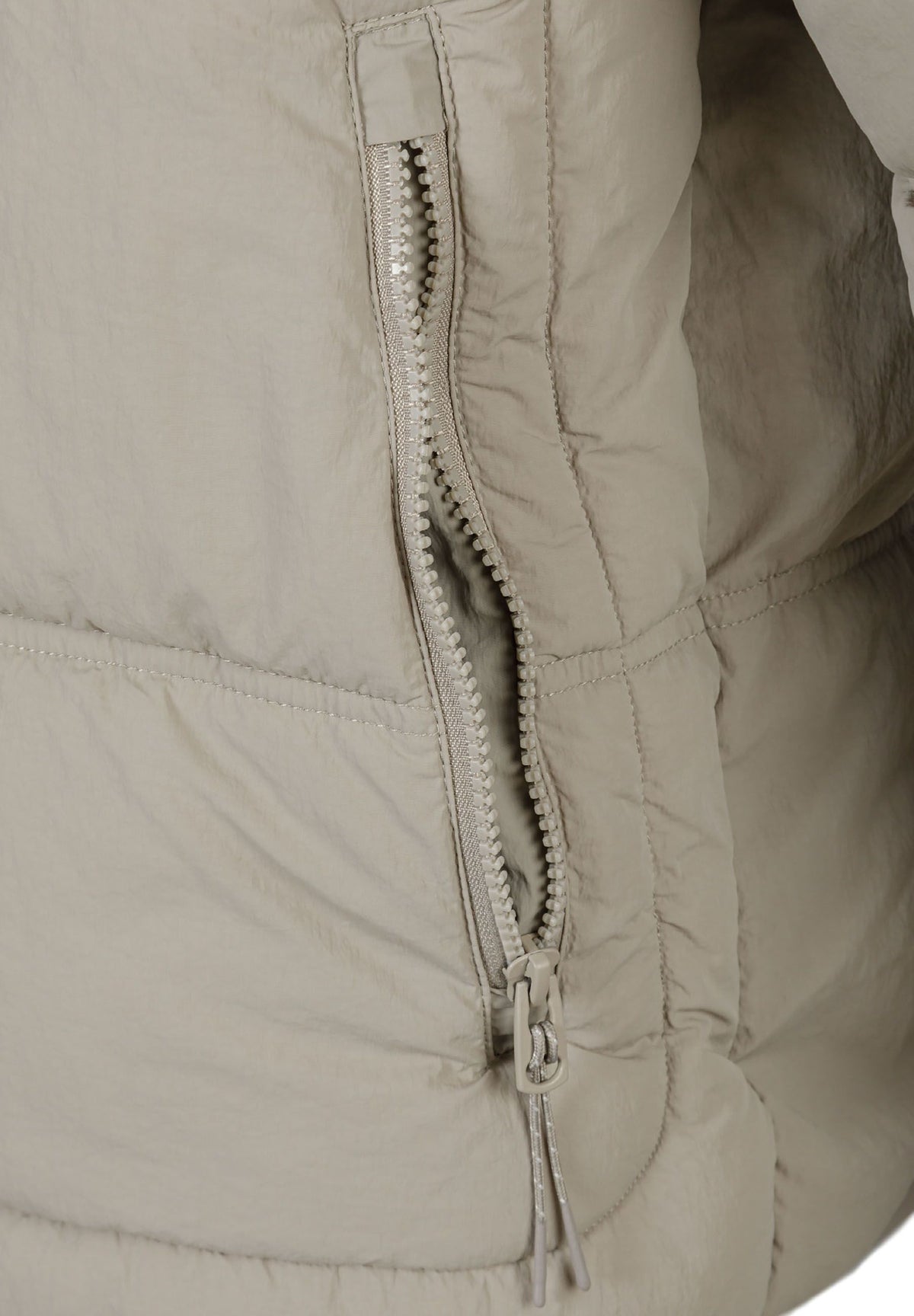 Close-up of the zip on the light beige puffer jacket.