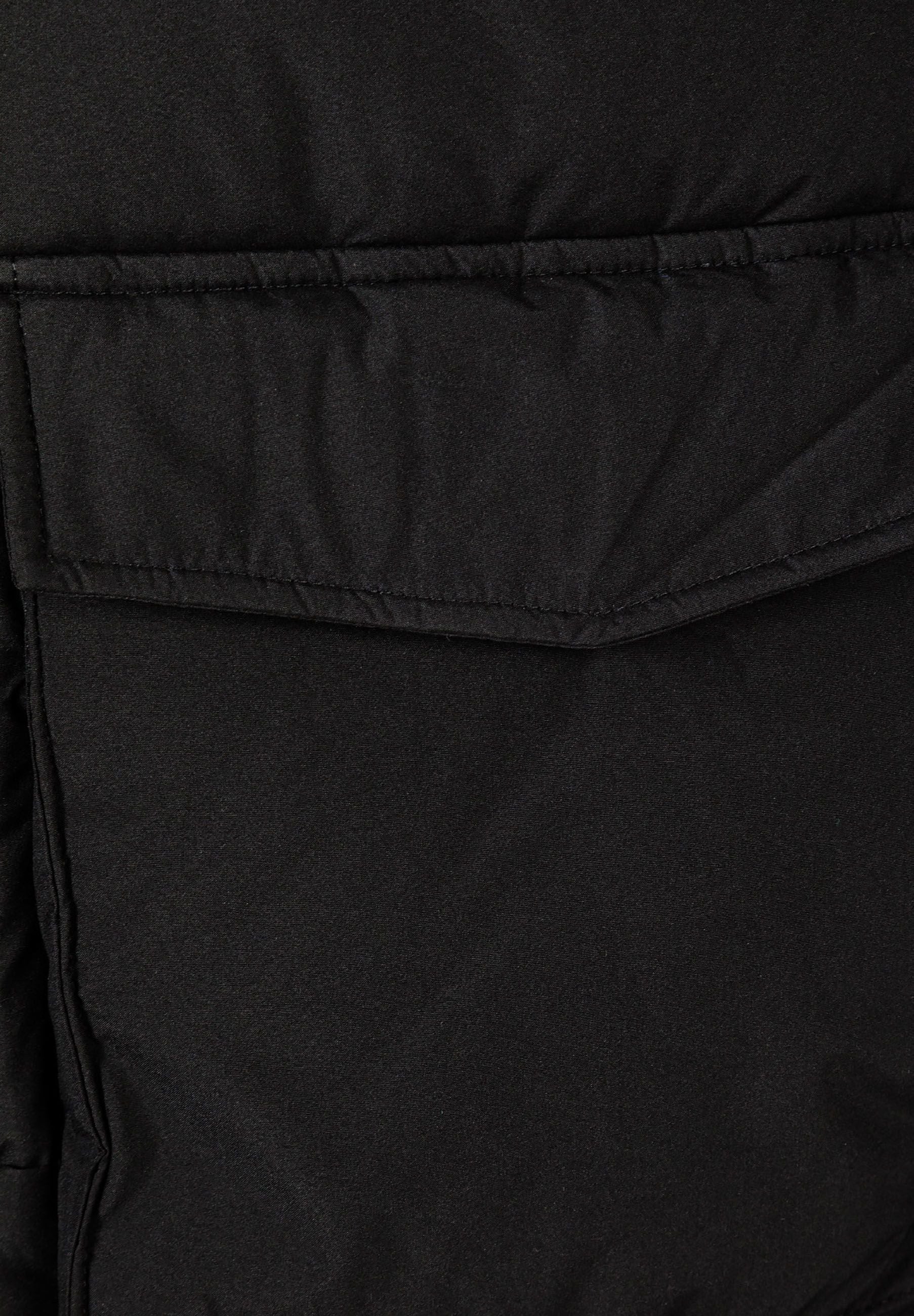 Detail of a black parka with a flap pocket and quilted texture.