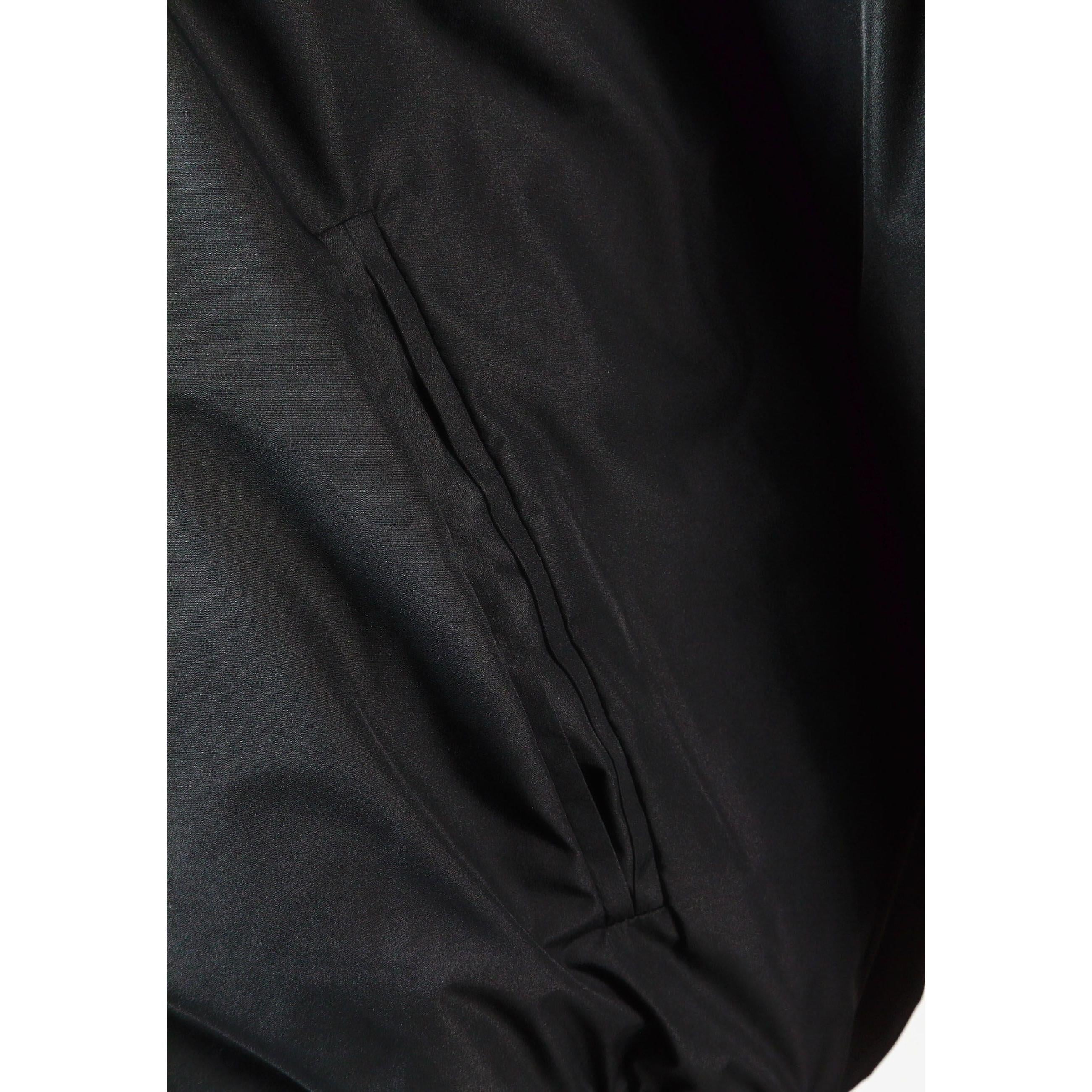 Close-up detail of black jacket showing zip closure with press studs and fabric texture