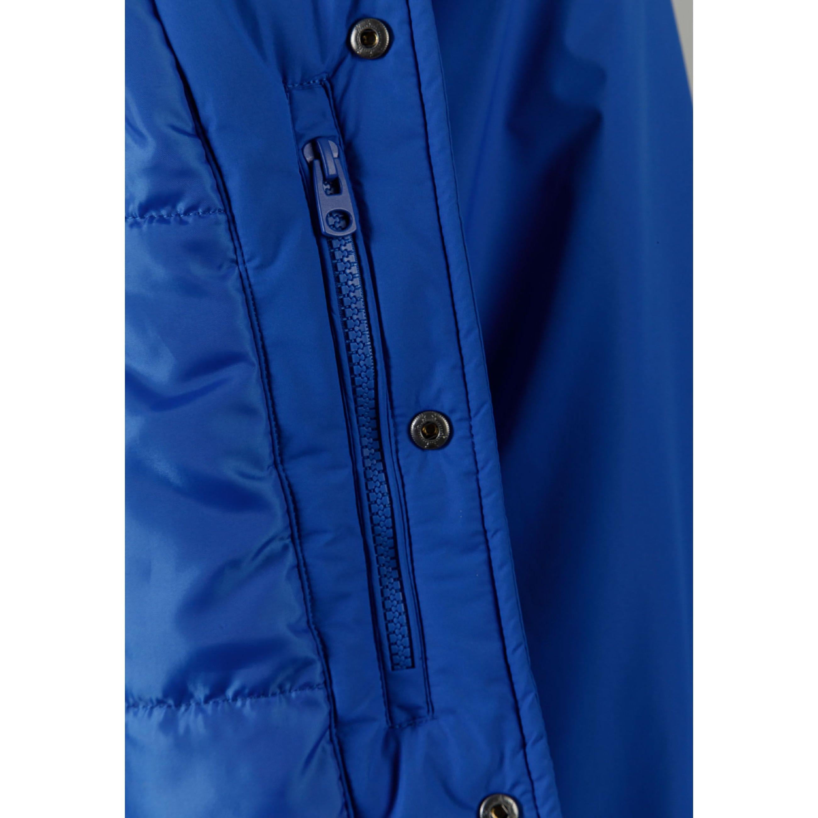 Close-up detail of cobalt blue jacket showing zip closure with matching blue zipper tape and snap button details