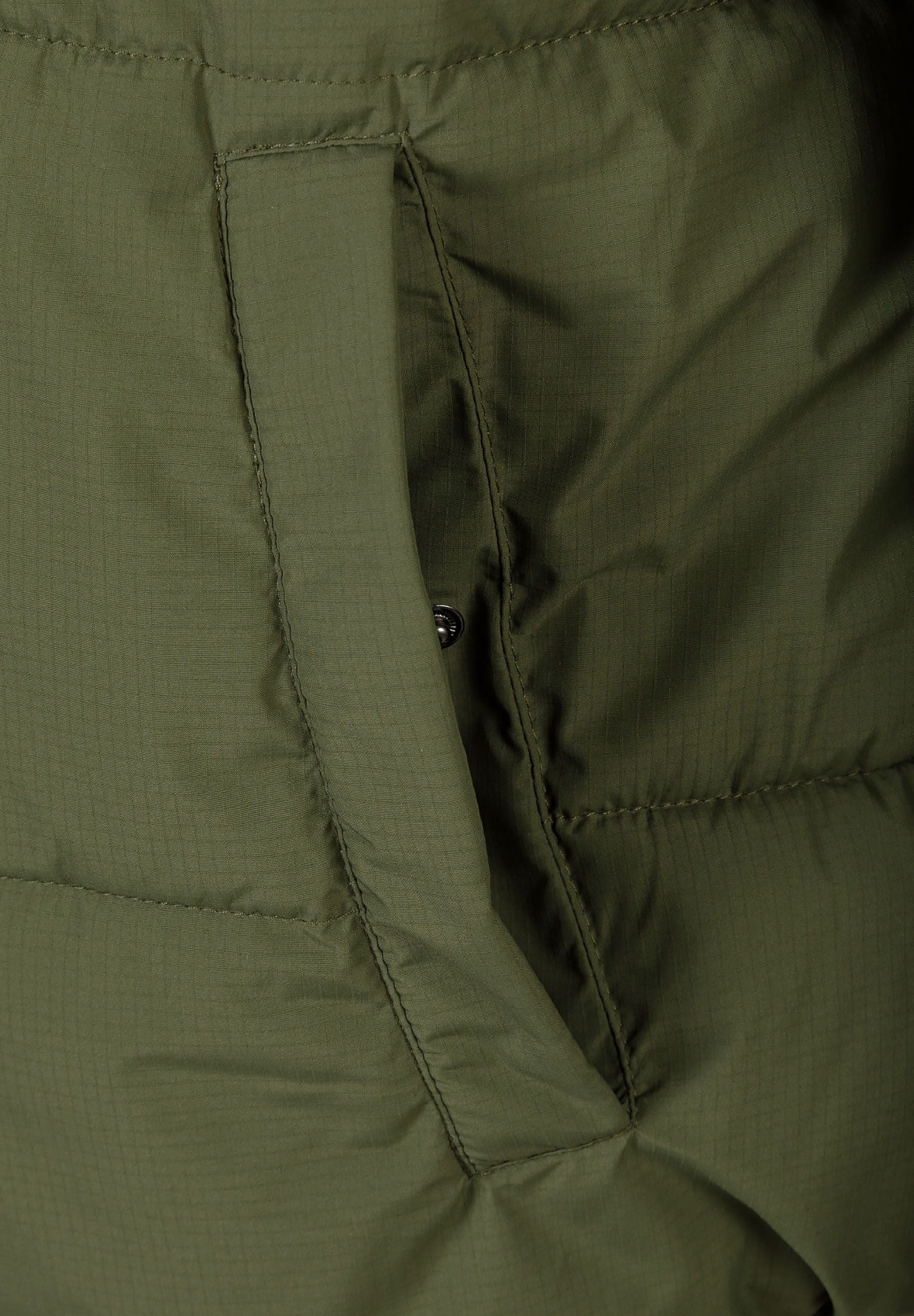 Detail of khaki men's ripstop jacket showing zippered pocket and fabric texture.