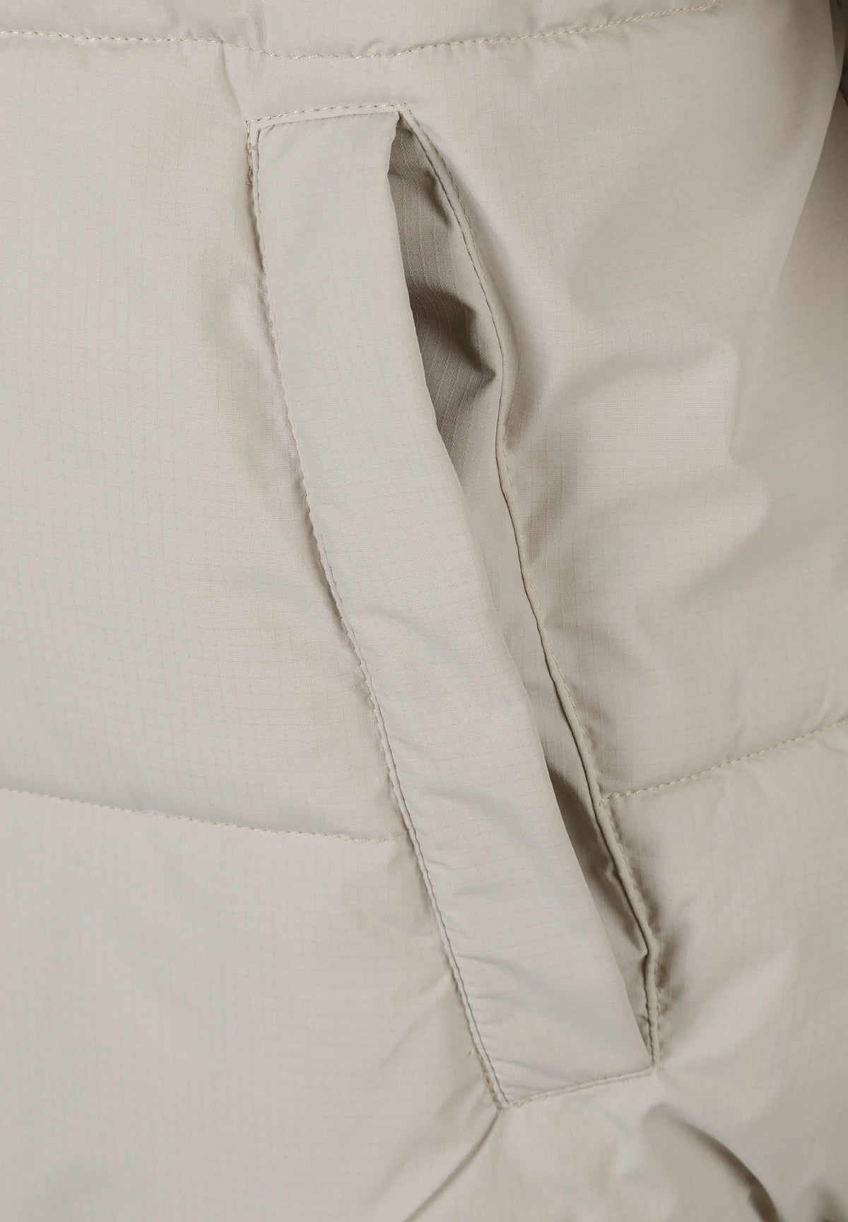 Close-up of the pocket on the light beige puffer jacket.
