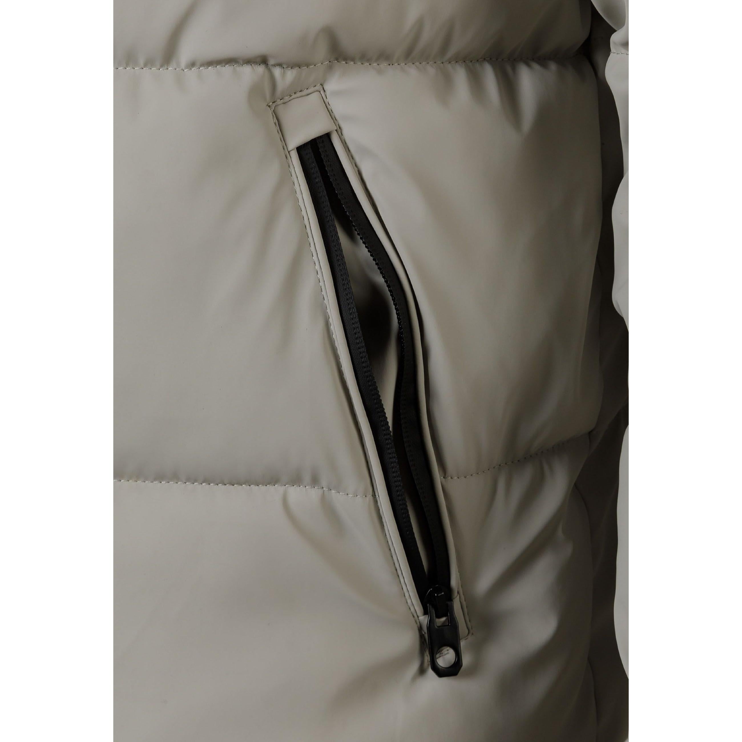 Close-up detail of side zip pocket on beige padded jacket showing black zipper and pocket construction