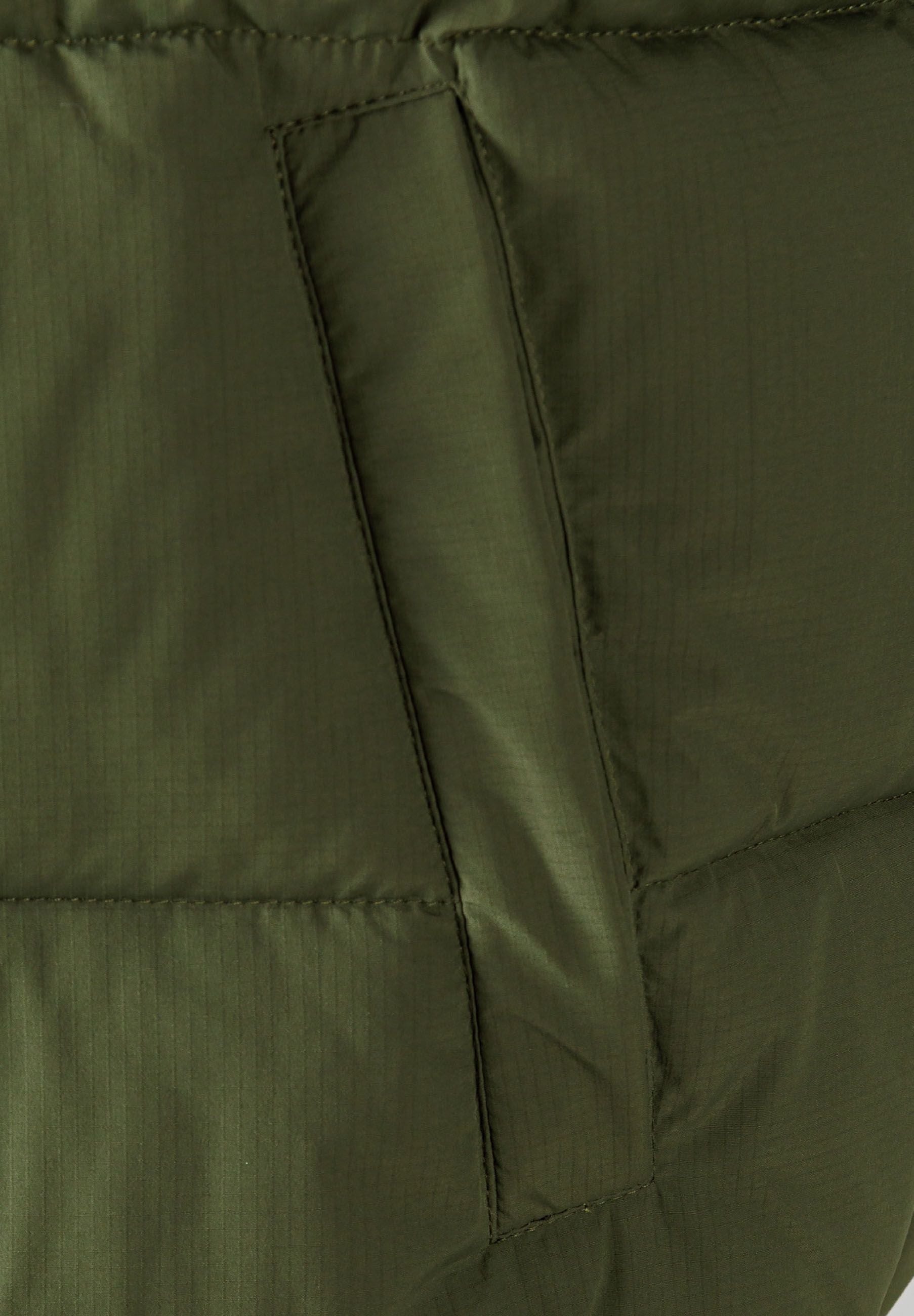 Detail of khaki padded gilet showing horizontal quilting and side pocket.