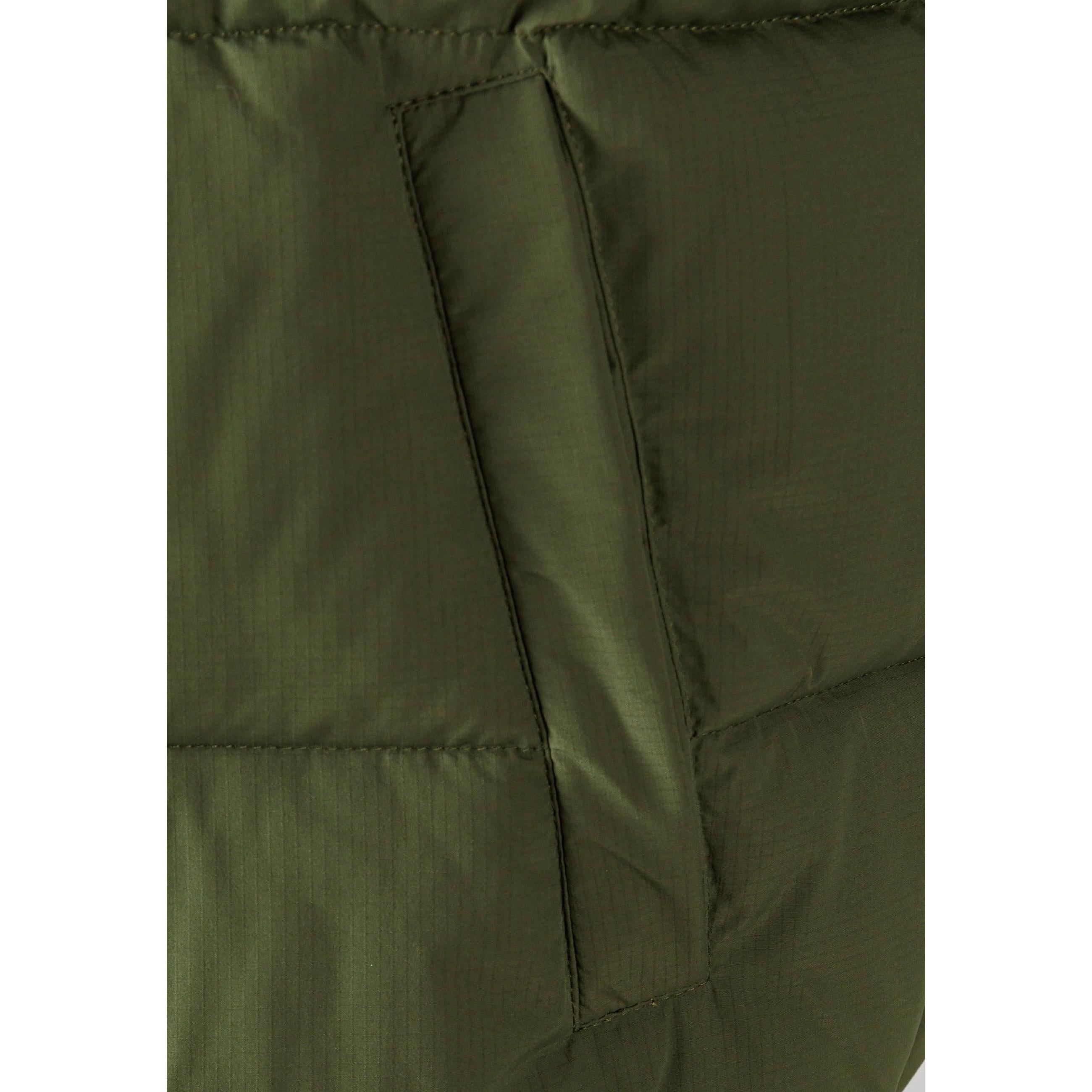 Close-up detail of khaki ripstop fabric showing side zip pocket with black zipper and horizontal quilting seams