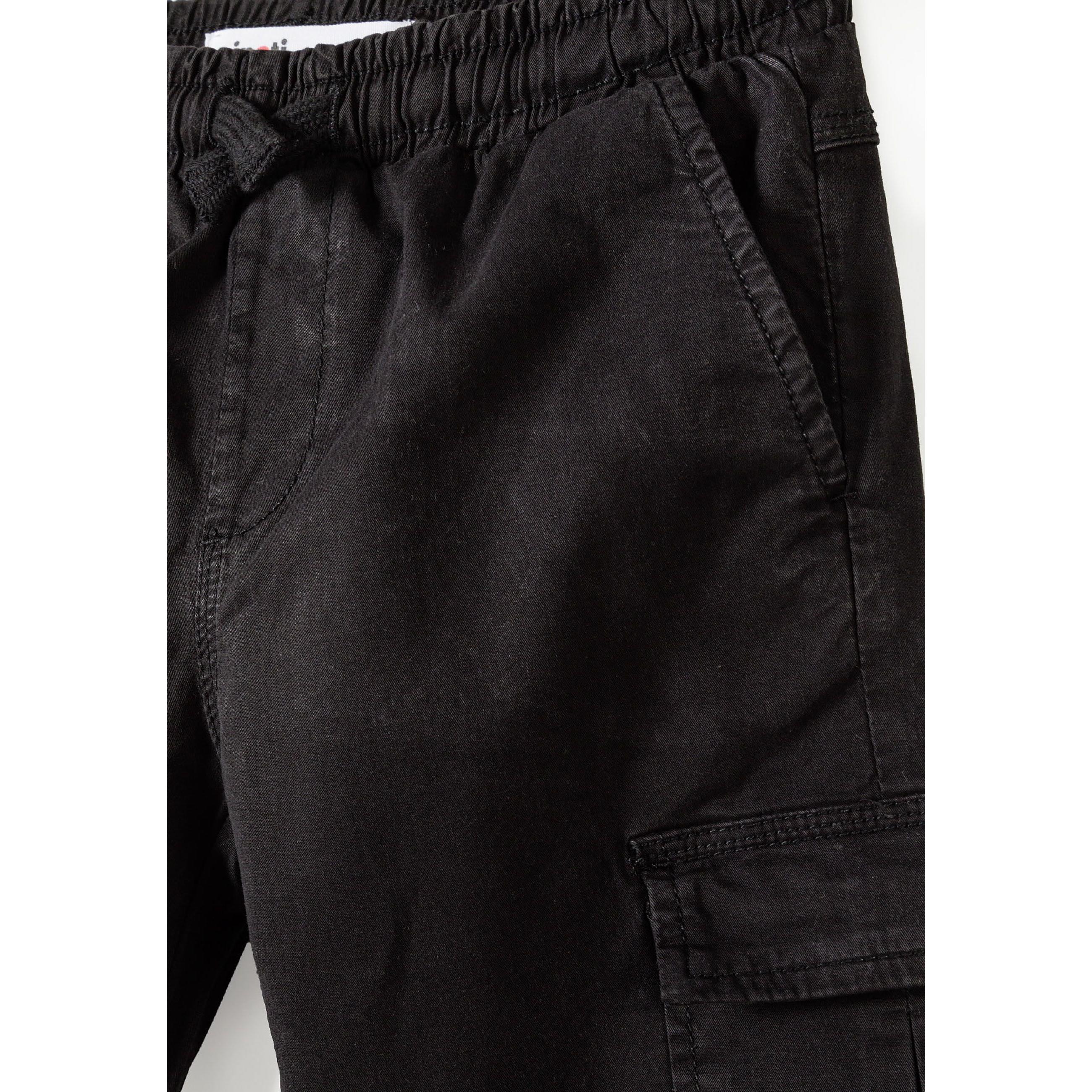 Close-up detail of black cargo trousers showing side cargo pocket and elasticated waistband construction
