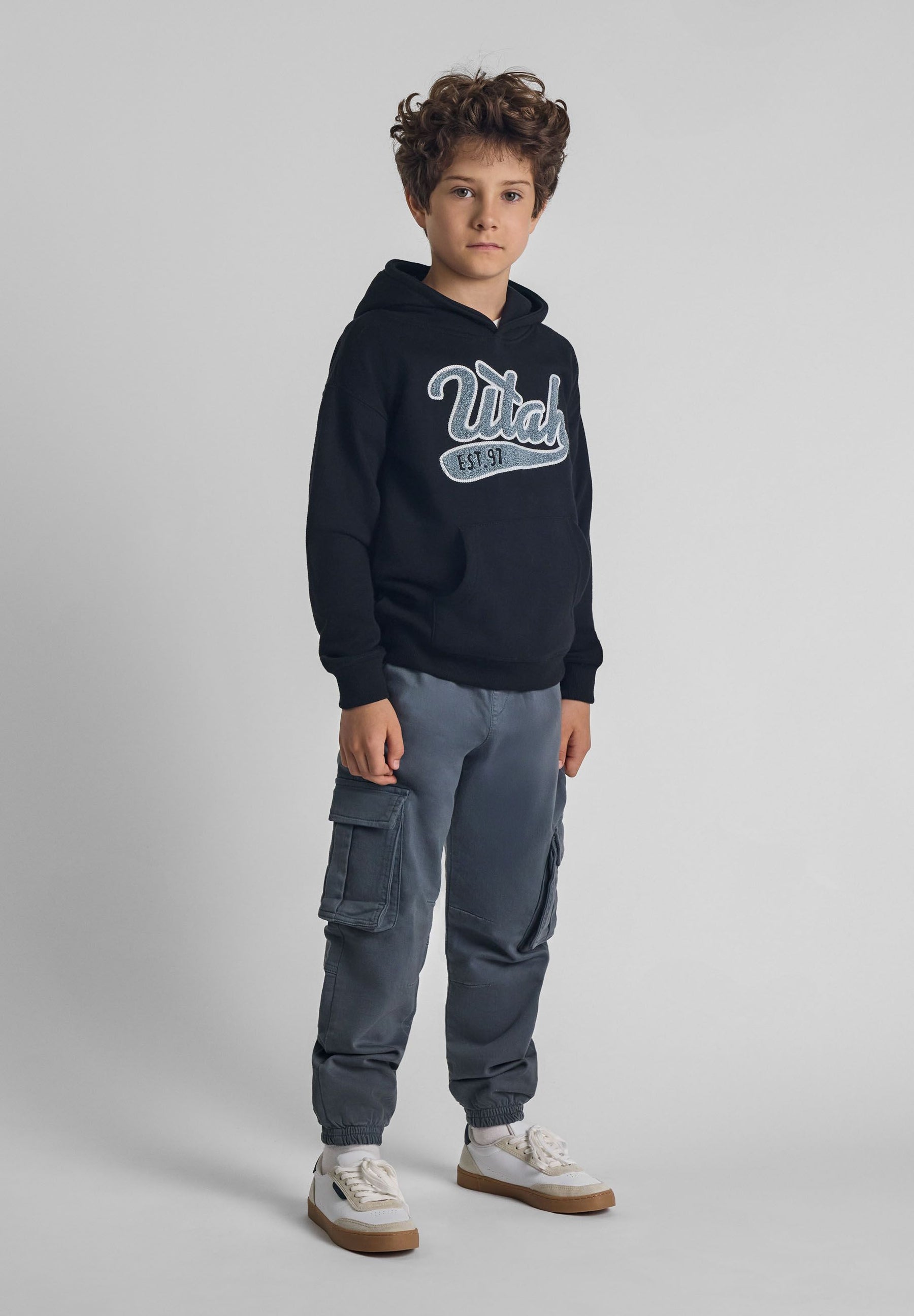 Boys cargo trousers with elastic waistband, front view, featuring side cargo pockets and ribbed ankle cuffs.