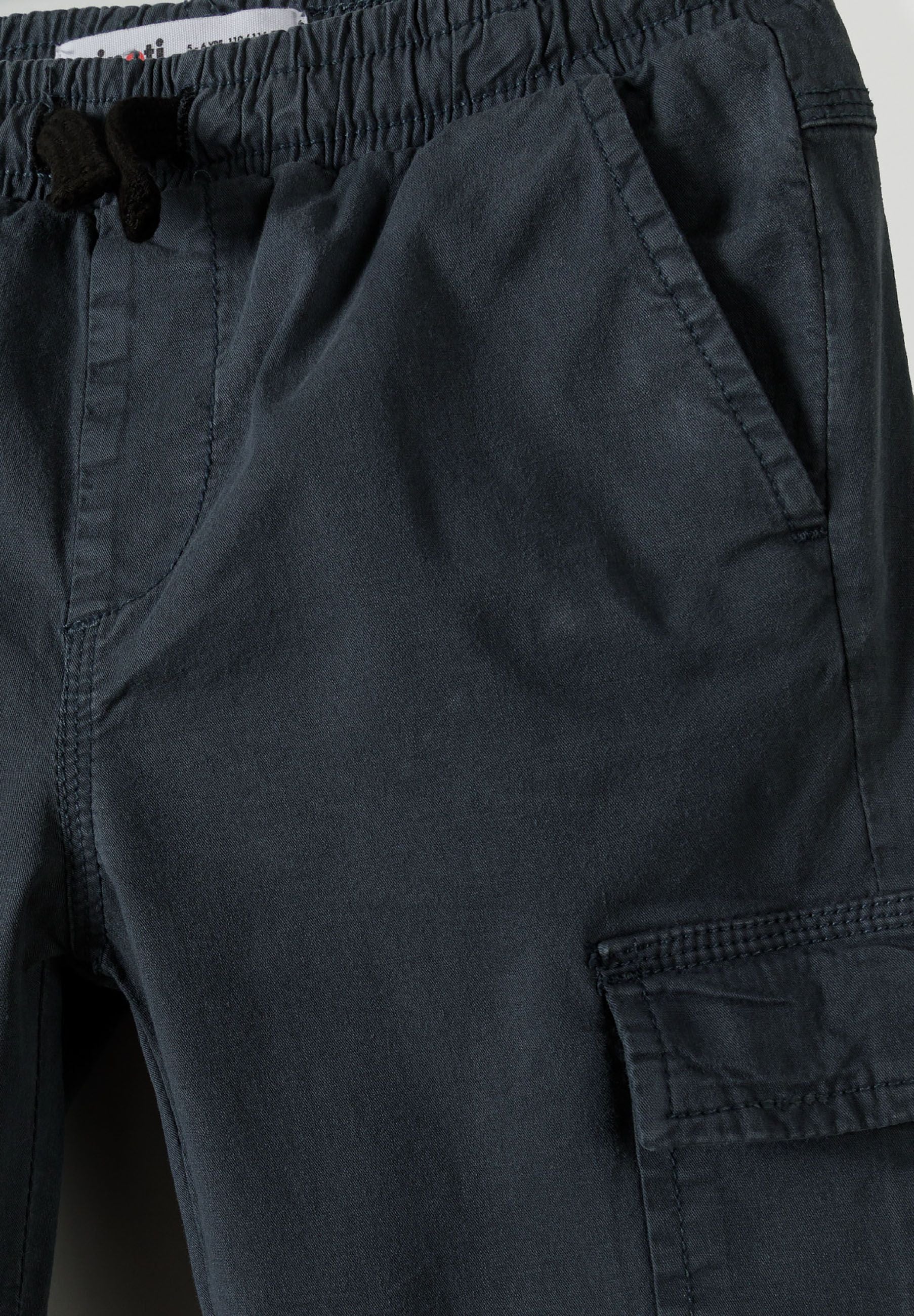 Close-up of boys' blue cargo trousers with elastic waistband and side pockets.