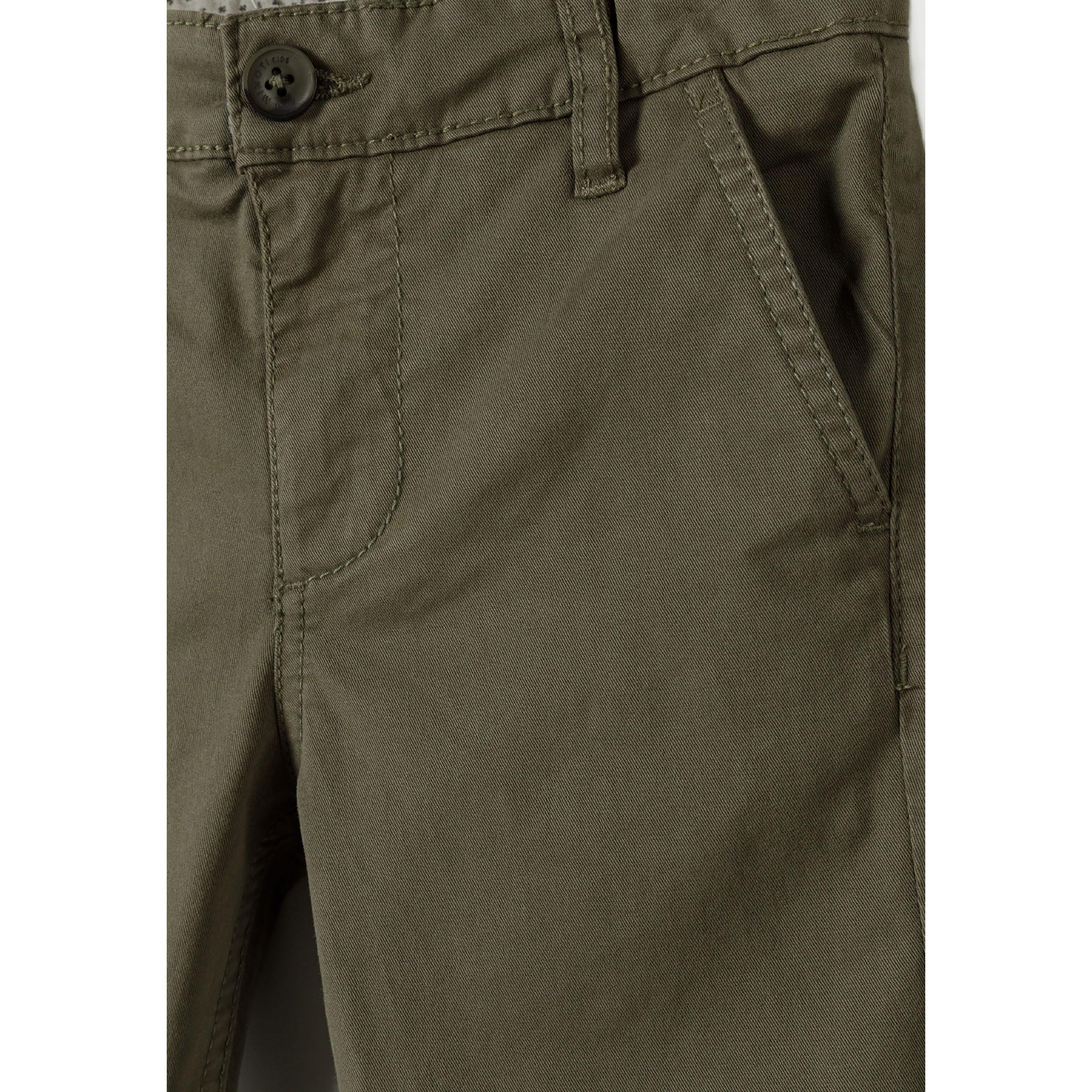 Close-up detail of khaki chino trouser waistband showing button closure and front pocket construction