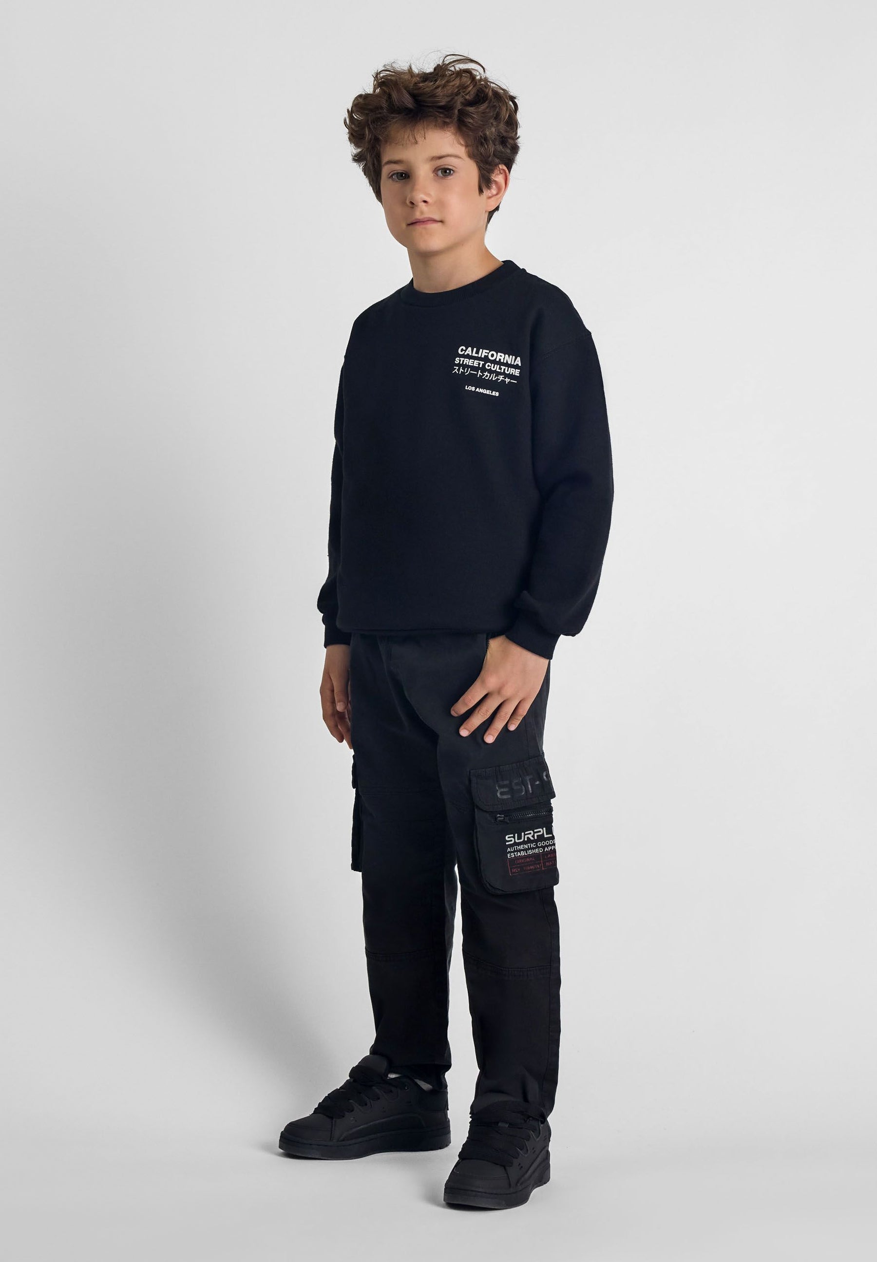 Boys cargo trousers in black, side cargo pocket with print, front view.