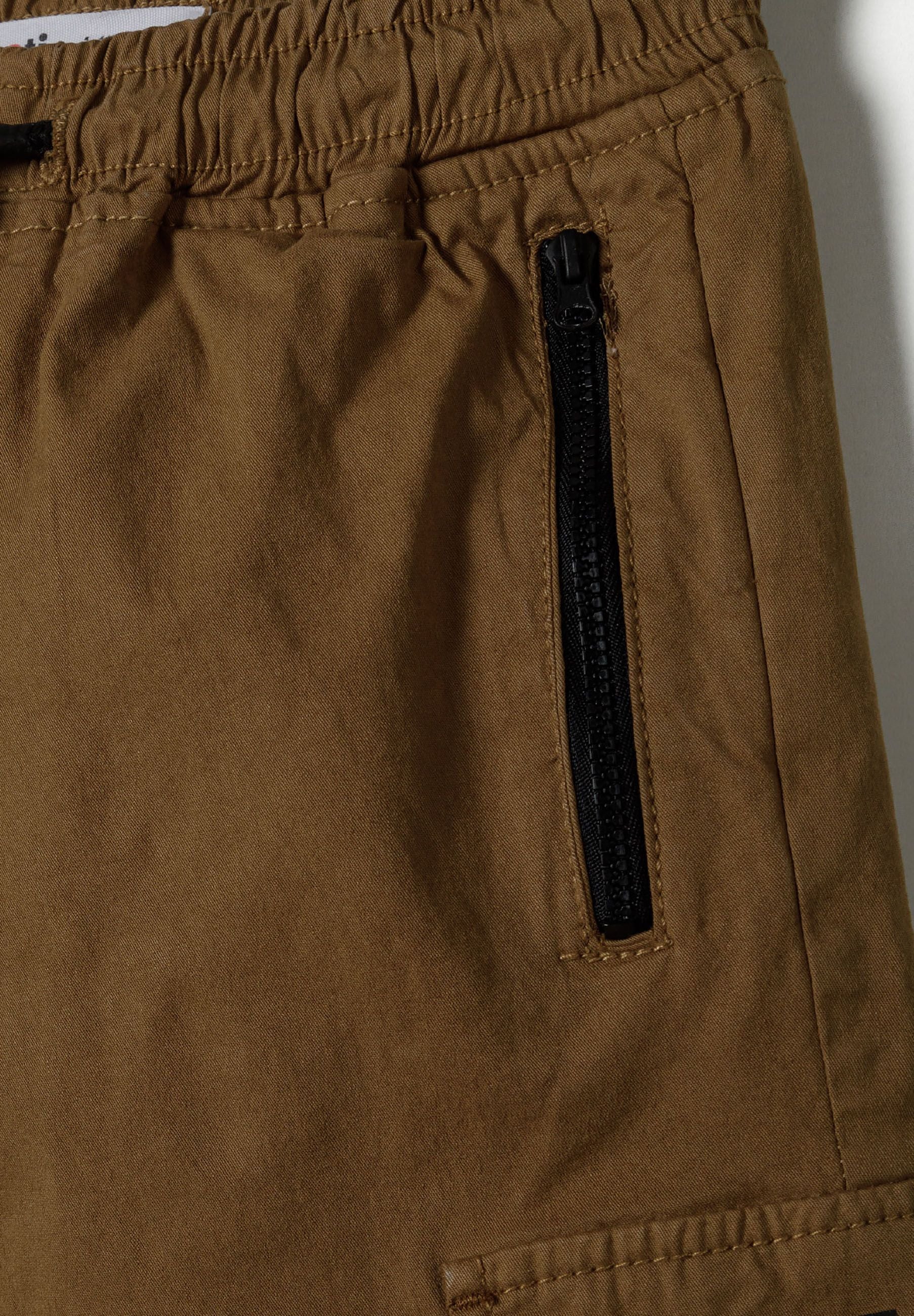 Detail of boys' beige cargo trousers featuring a zip pocket.