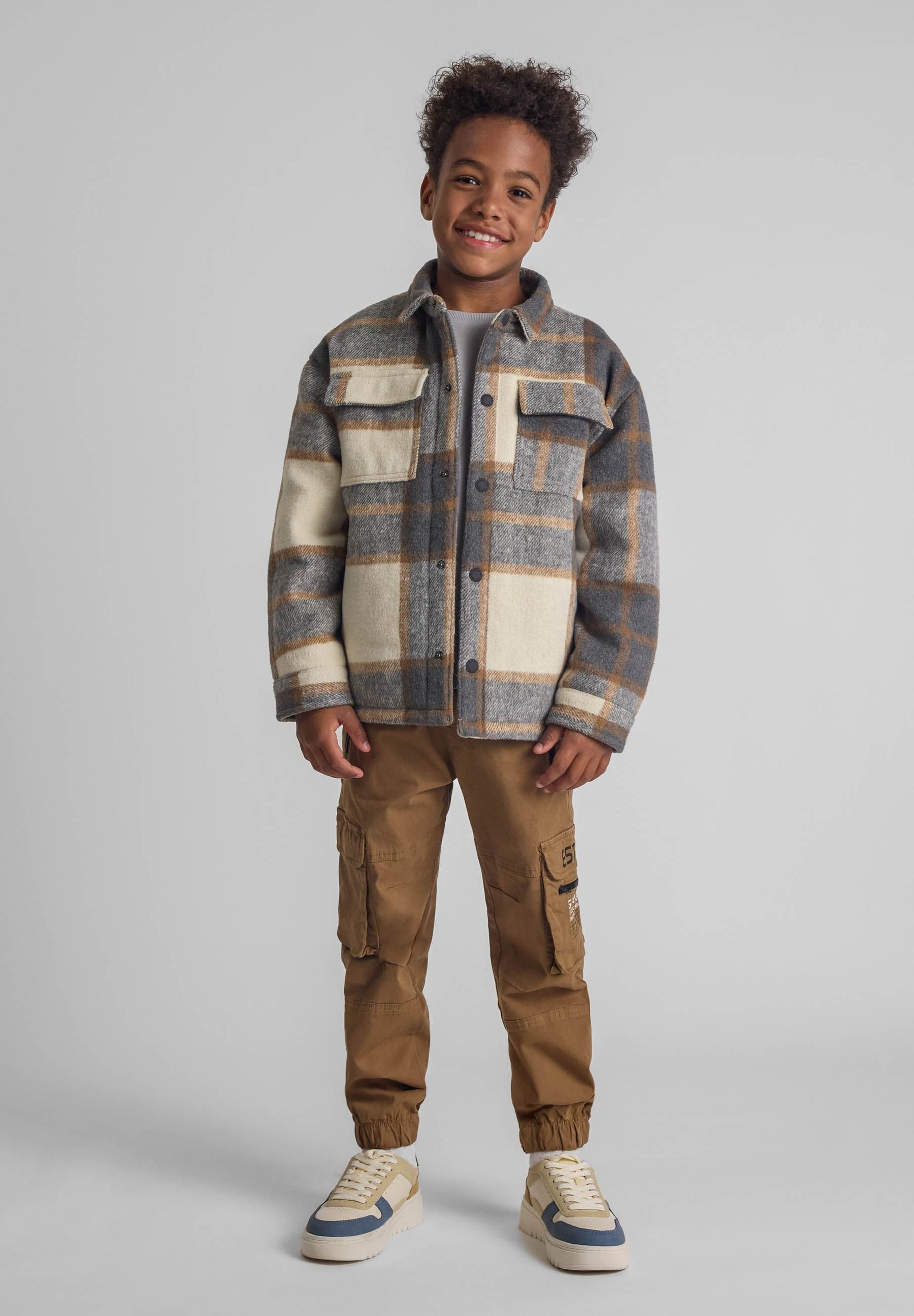 Boys beige cargo trousers with zip pockets, front view.