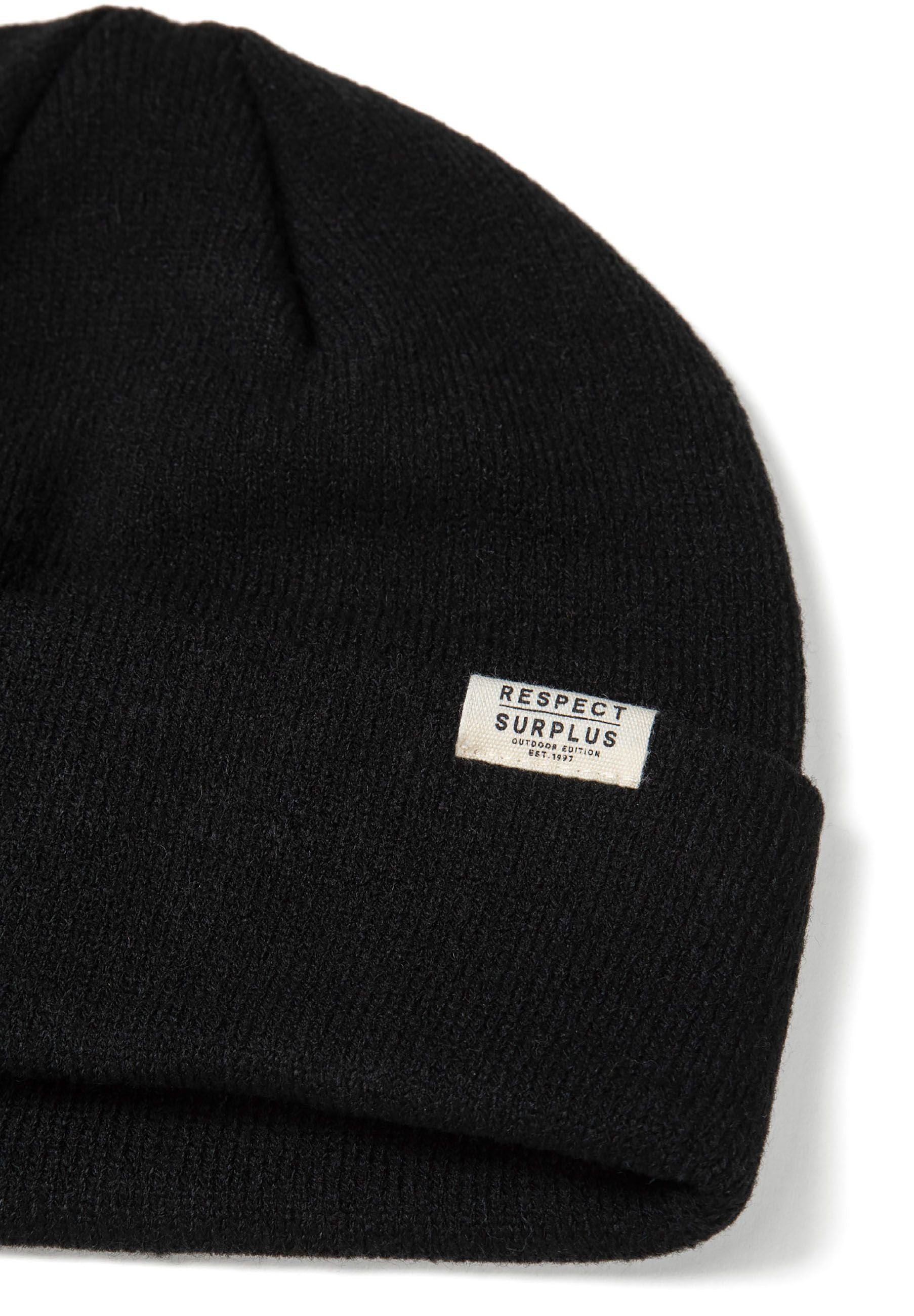 Detail of a black ribbed beanie hat with a fold-up cuff and logo badge.