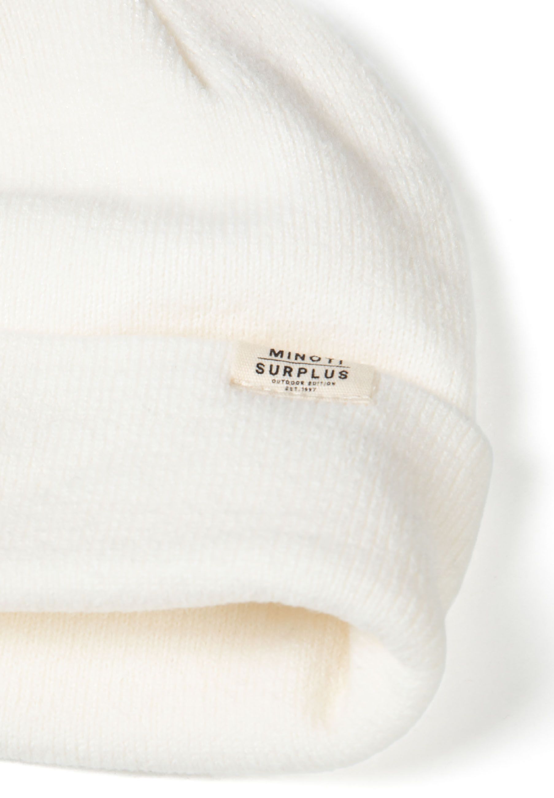 Detail of a ribbed knit beanie hat in white with a folded brim and a small logo badge.