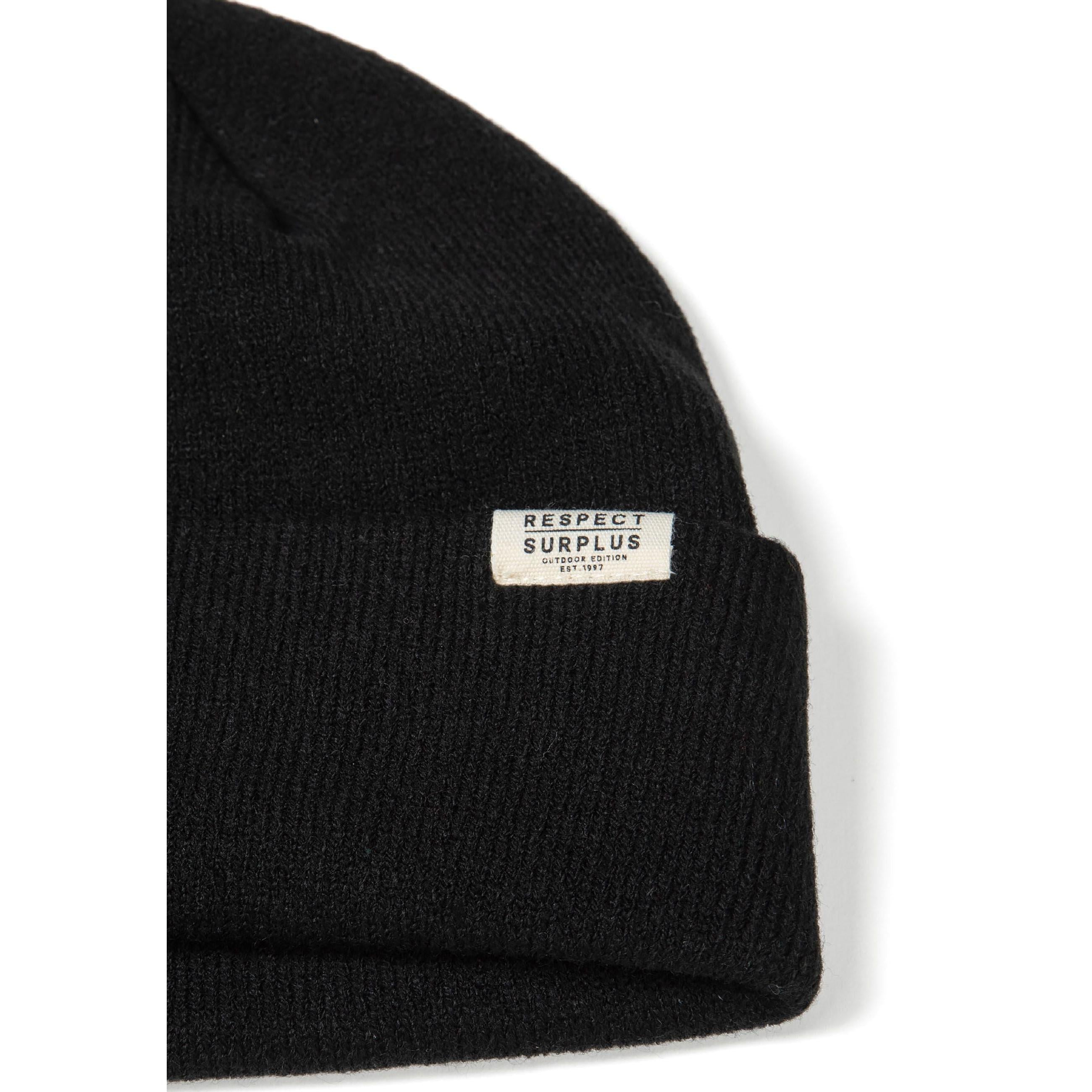 Single grey ribbed knit beanie with folded cuff and small rectangular white brand label, photographed flat against white background