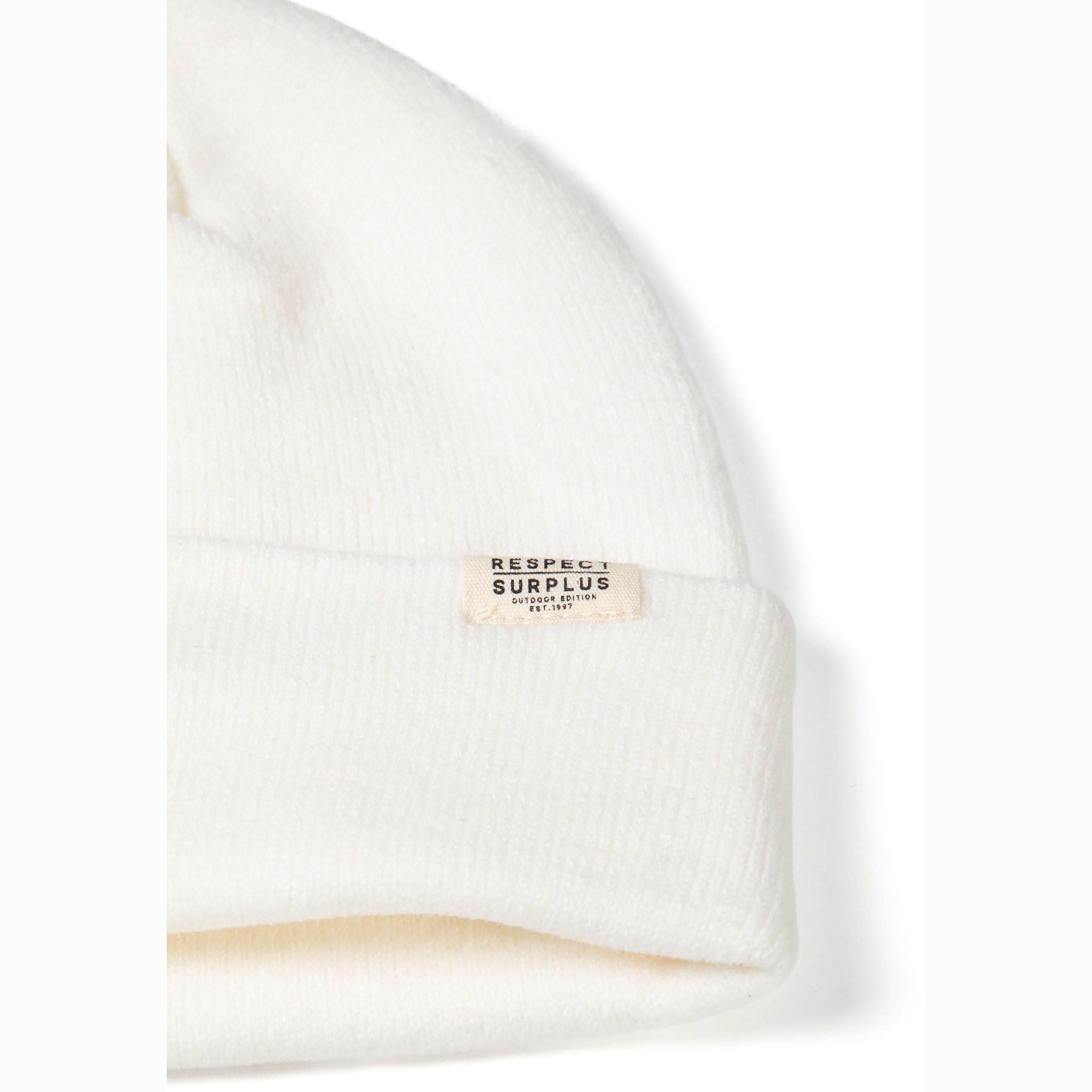 Single grey ribbed knit beanie with folded cuff and small rectangular white brand label, photographed flat against white background