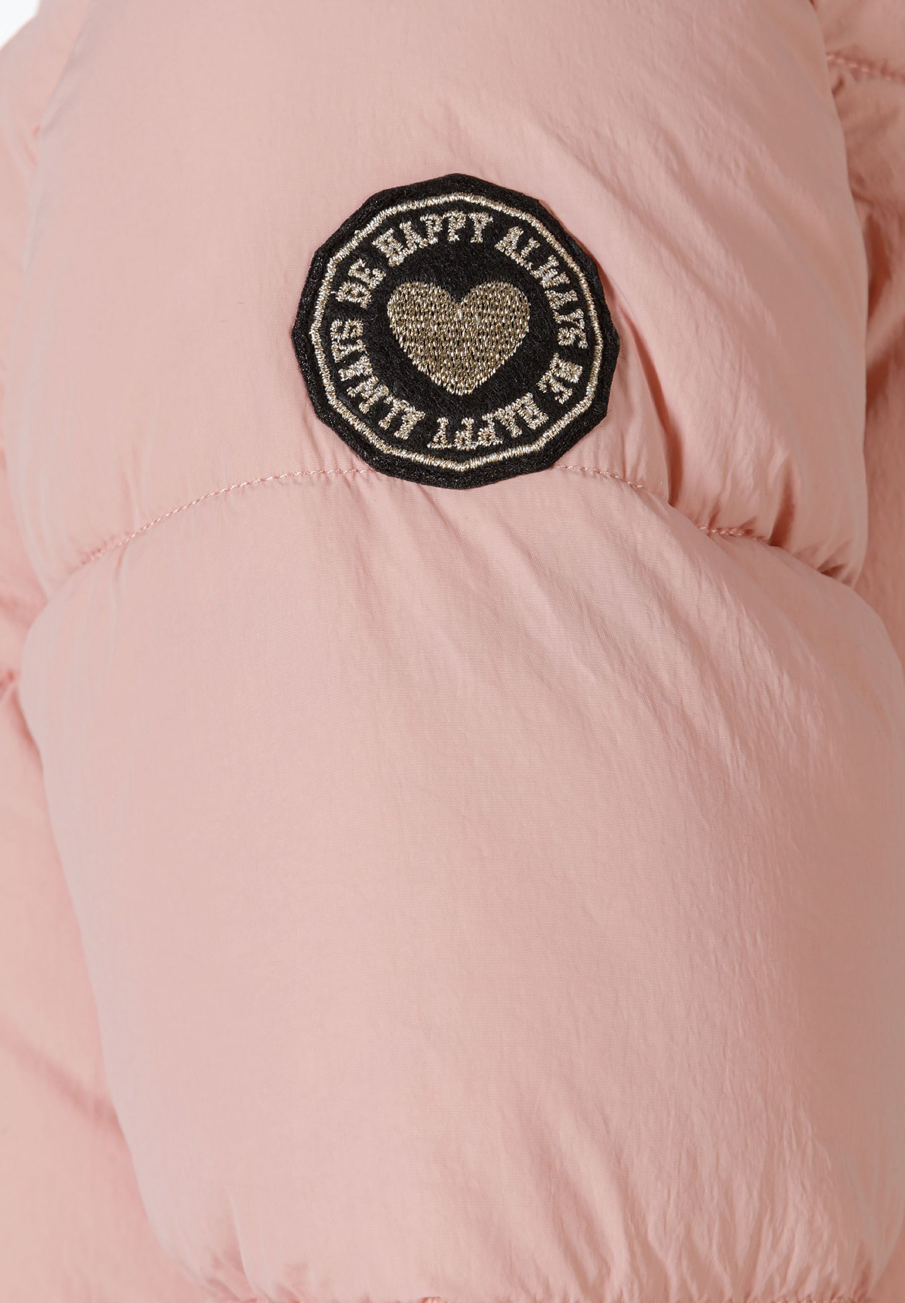 Detail of a pink quilted winter jacket with a decorative patch on the sleeve.