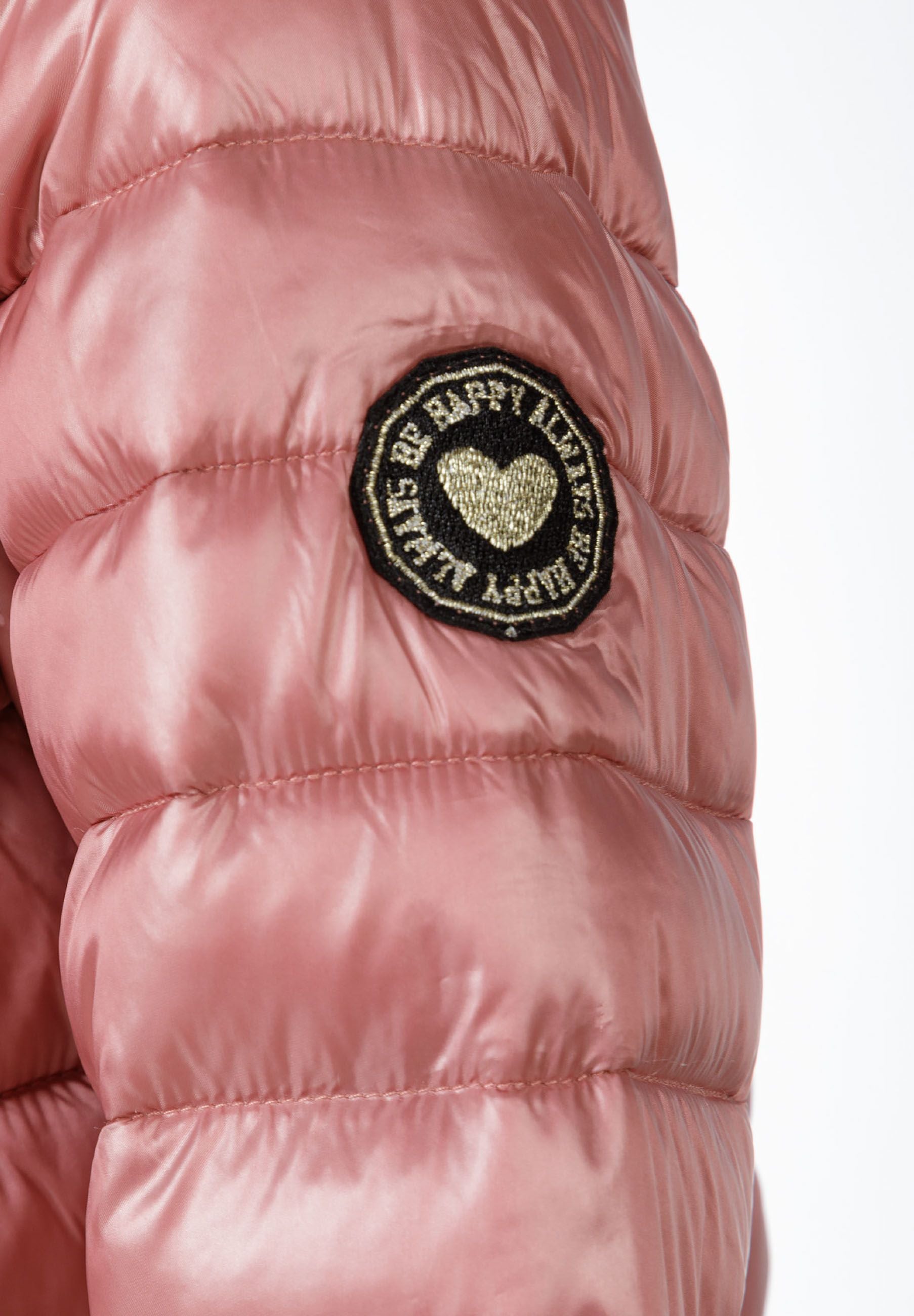 Detail of a girls' quilted jacket sleeve with a heart-shaped badge.