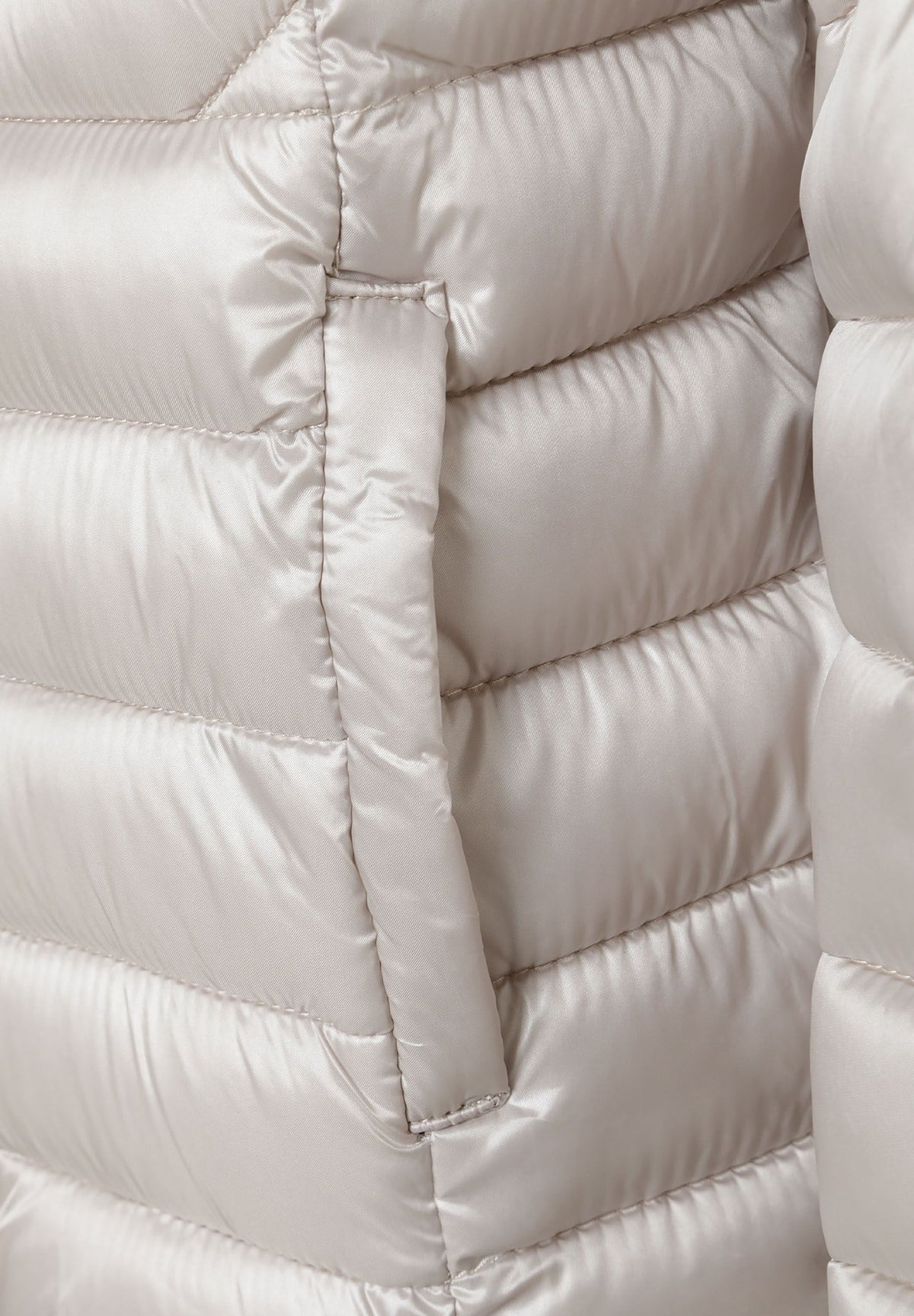 Close-up of the pocket on the light grey puffer jacket.