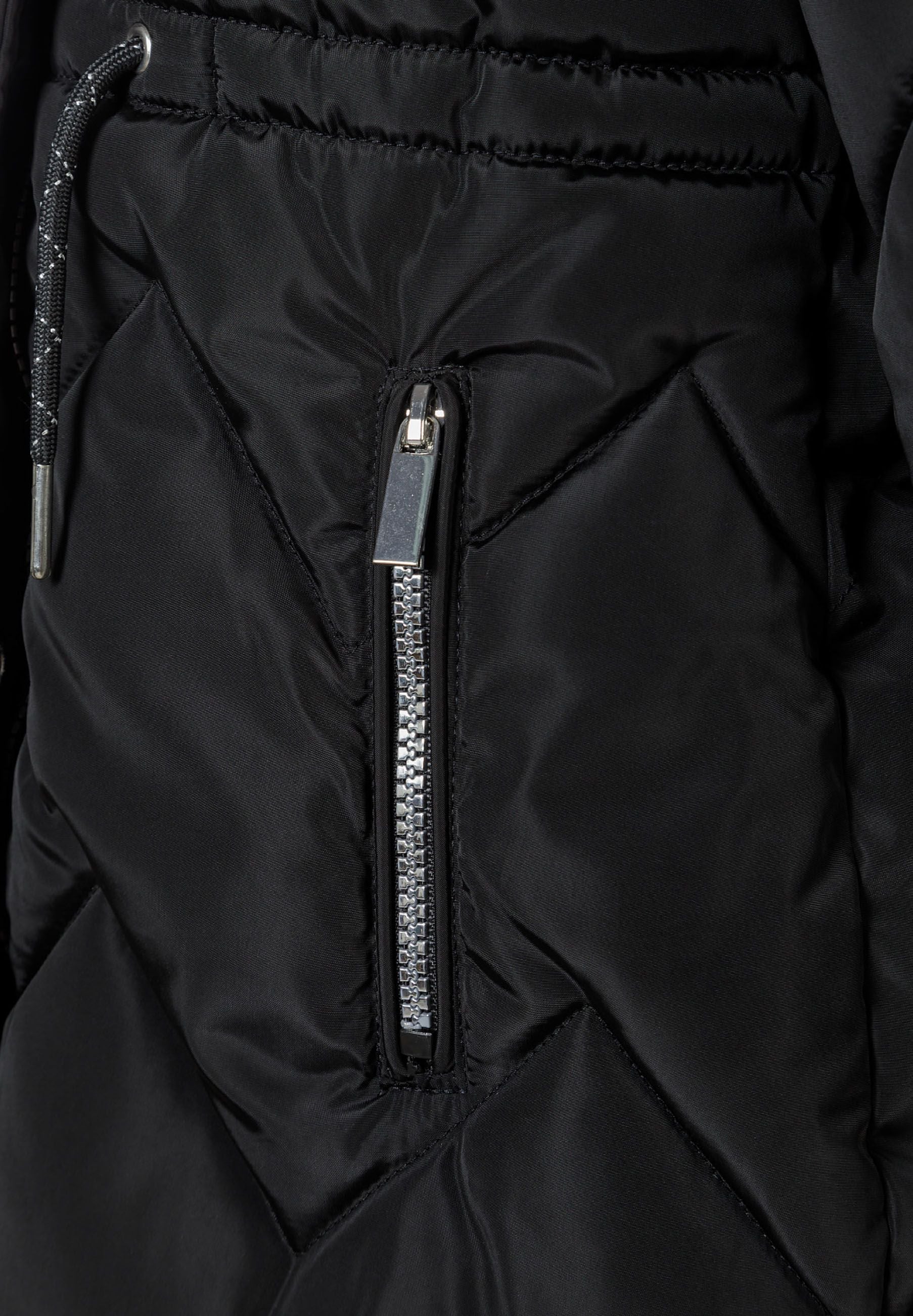 Detail of a black quilted winter jacket with a zippered pocket.