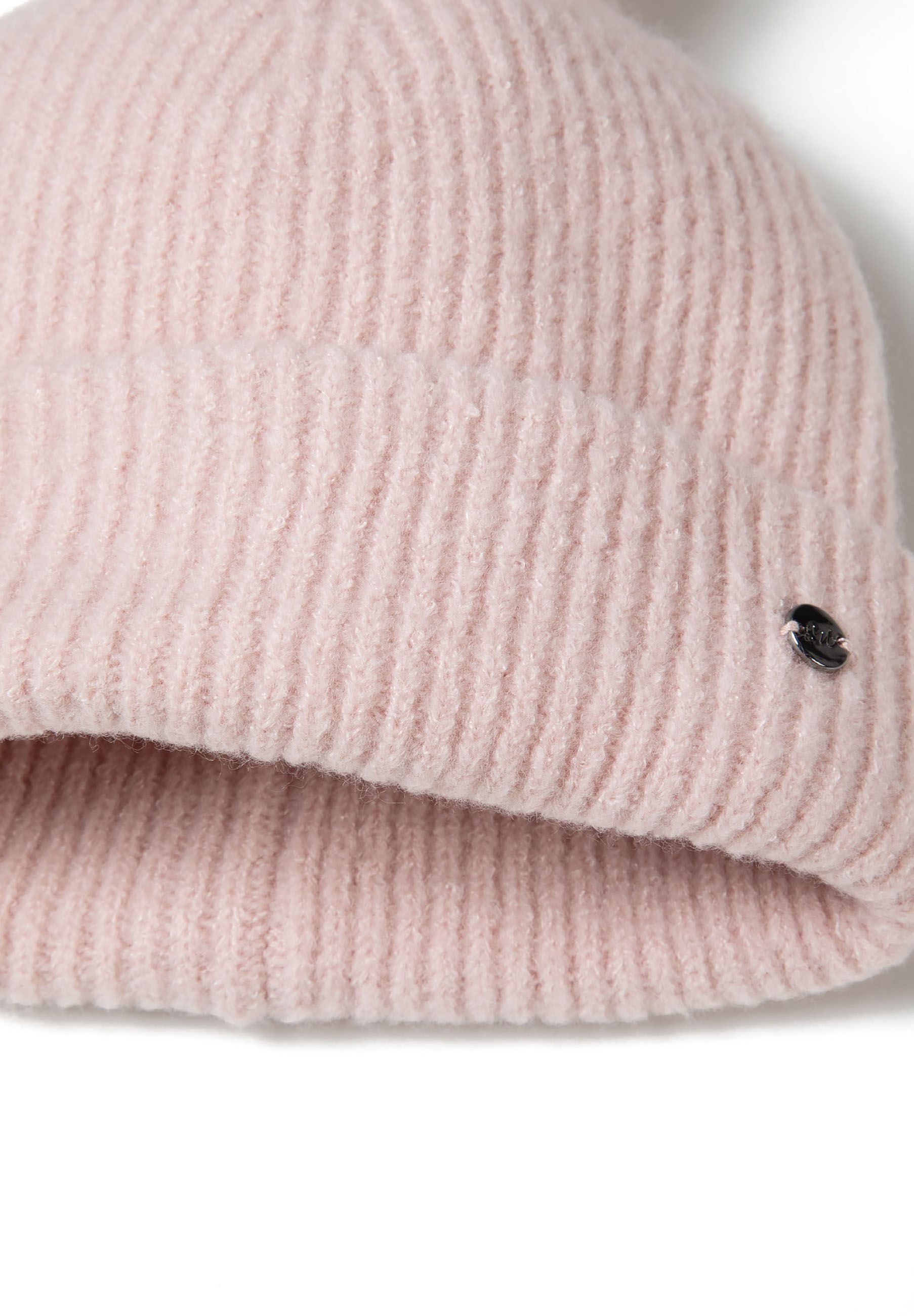Detail of pink ribbed knit gloves with elasticated cuffs and a metal badge.