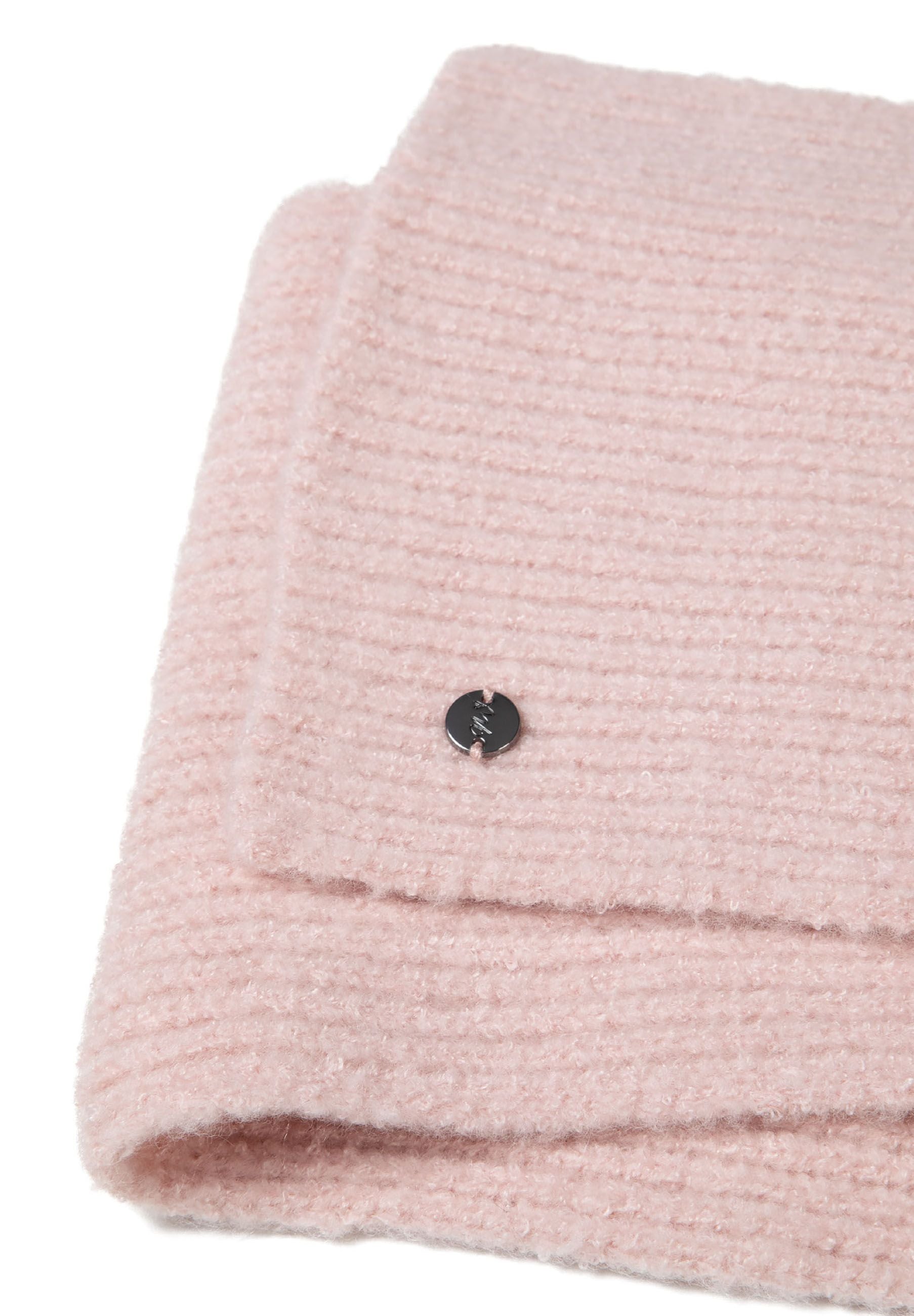 Detail of a pink ribbed scarf with a small metal badge.