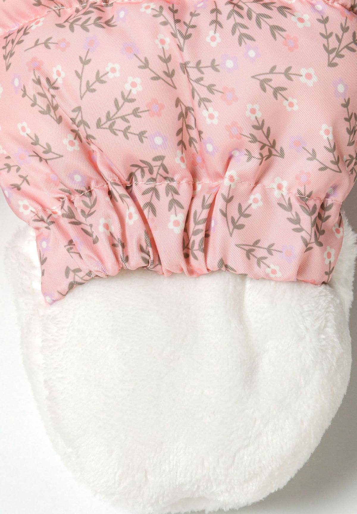 Detail of girls baby snowsuit in light pink with floral pattern and soft white lining.