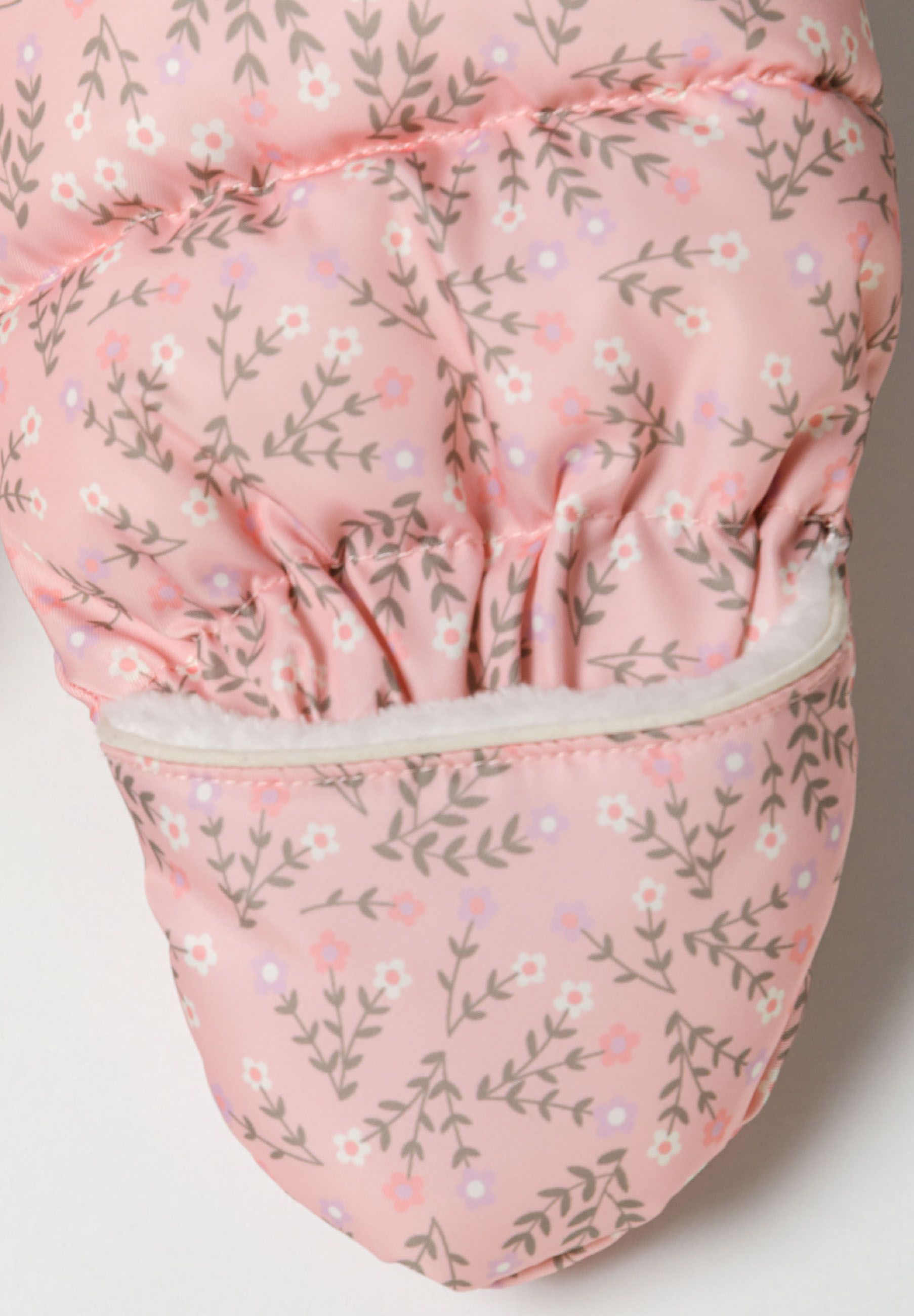 Detail of a girls baby snowsuit in light pink with floral pattern and double zip.
