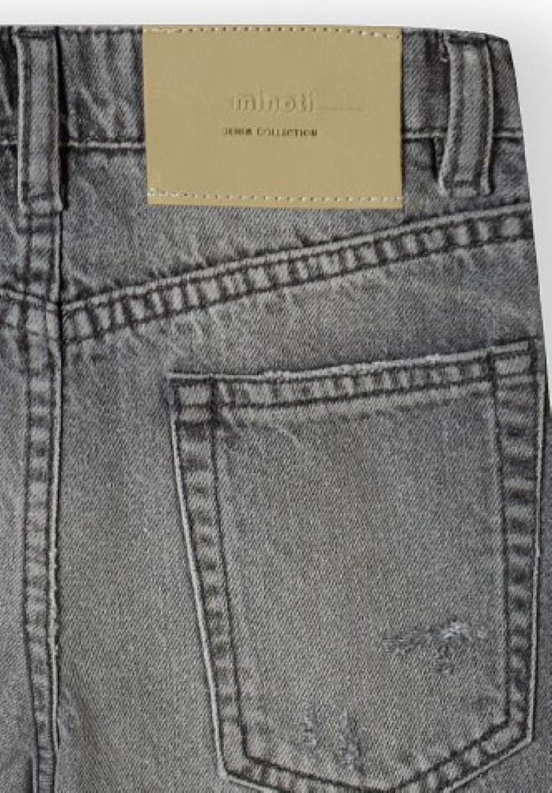 Close-up of grey jean back pocket and pale Minoti Denim Collection waist patch.