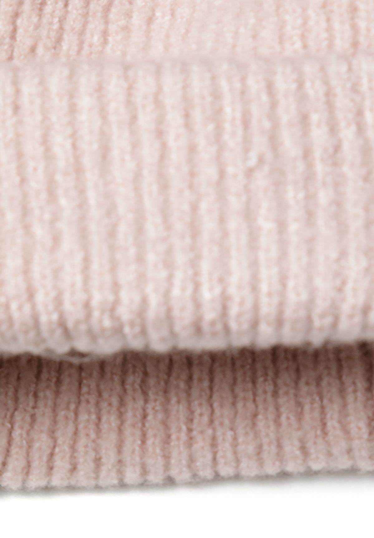 Extreme close-up of pale pink ribbed knit layers on scarf edge.