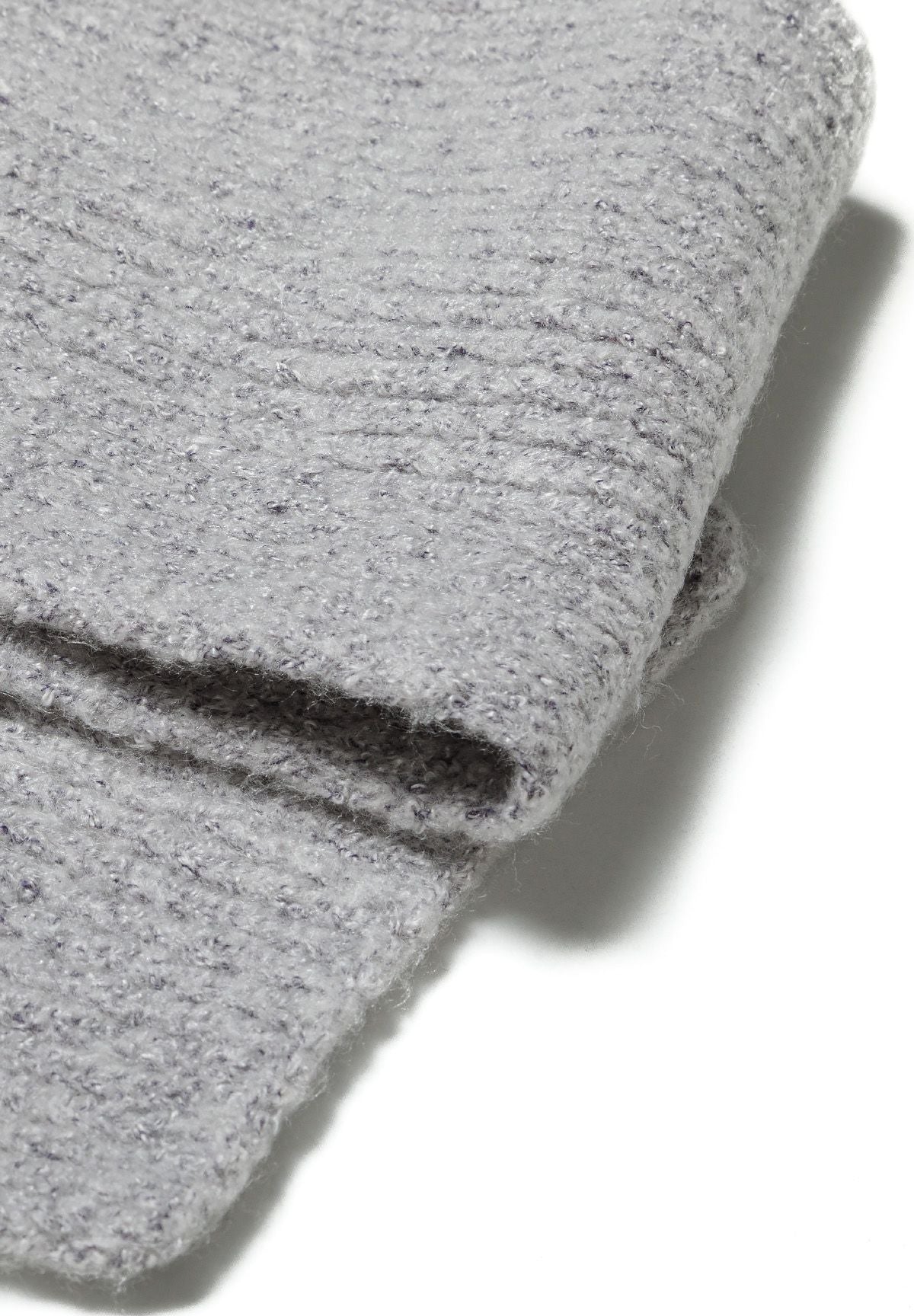 Close-up of folded grey marl scarf edge and brushed knit surface.