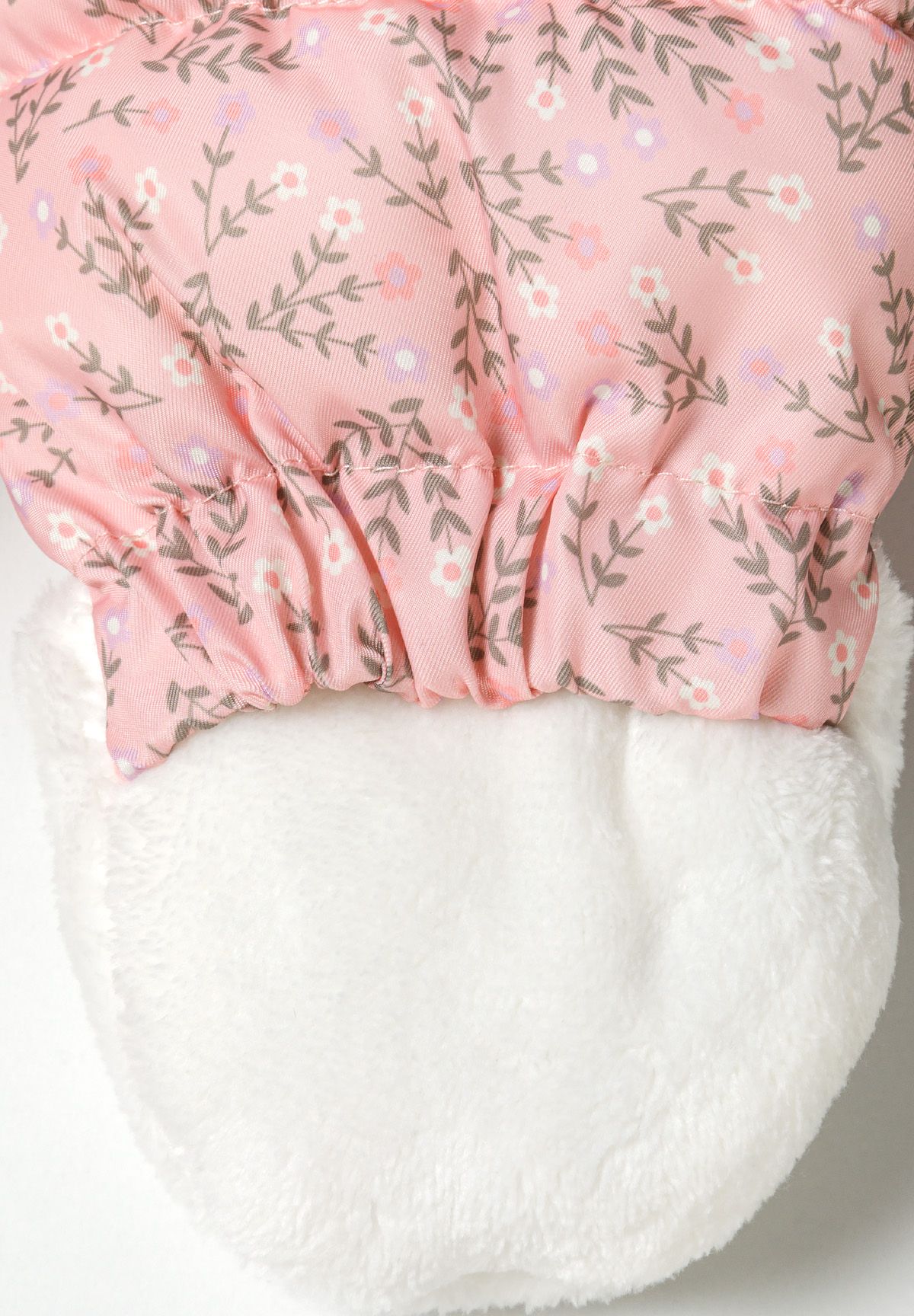 Folded-back pink snowsuit mitten revealing white plush lining at gathered wrist.