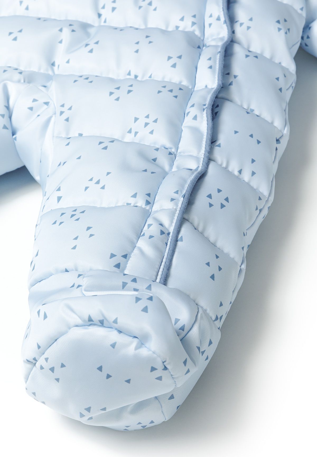 Close-up of covered foot on blue triangle-print snowsuit beside a front zipper.